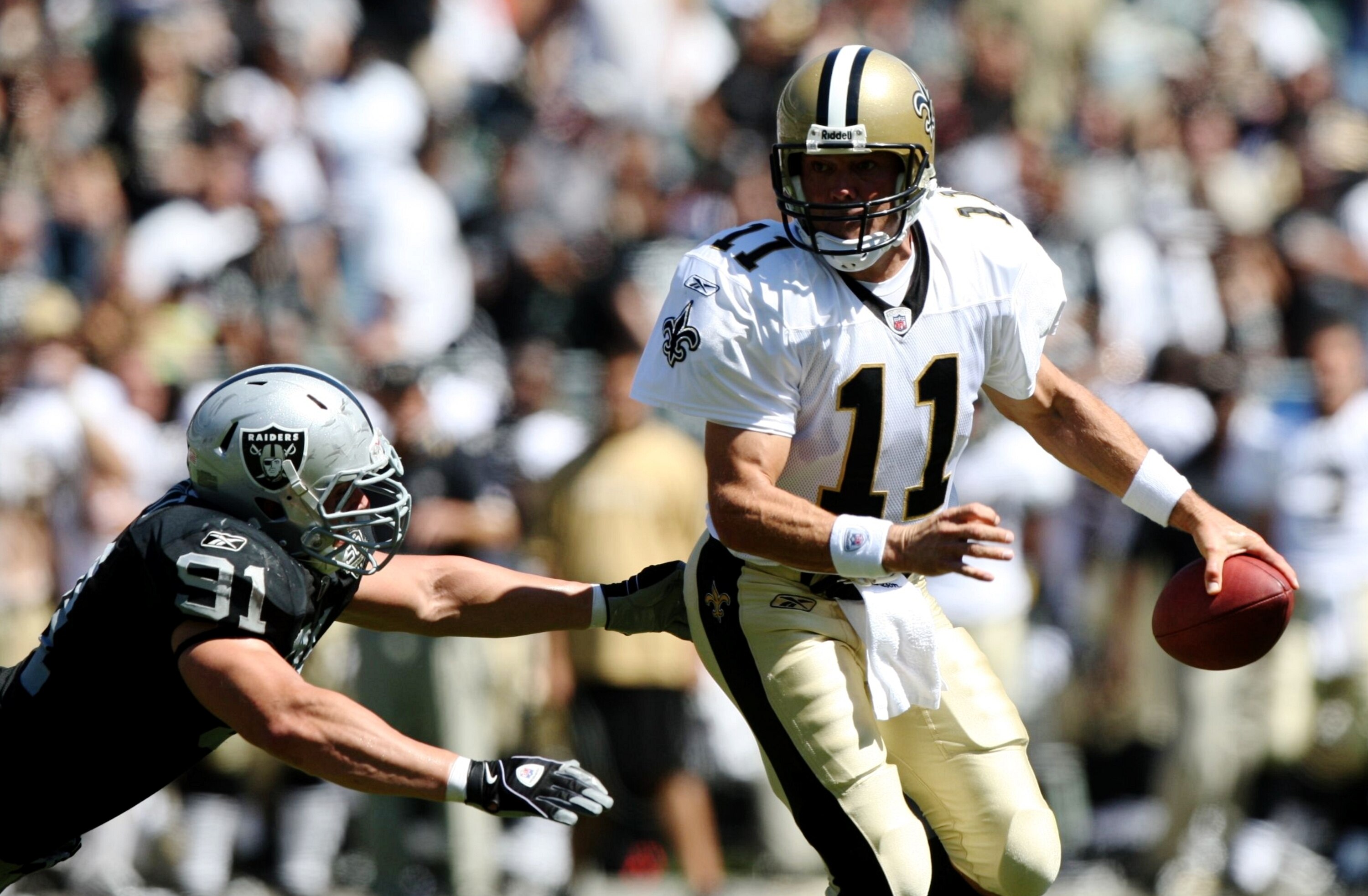 OAKLAND, CA - AUGUST 29:  Quarterback Mark Brunell #11 of the New Orleans Saints rolls out to pass against Trevor Scott #91 of the Oakland Raiders during the preseason game at Oakland-Alameda County Coliseum on August 29, 2009 in Oakland, California. (Pho