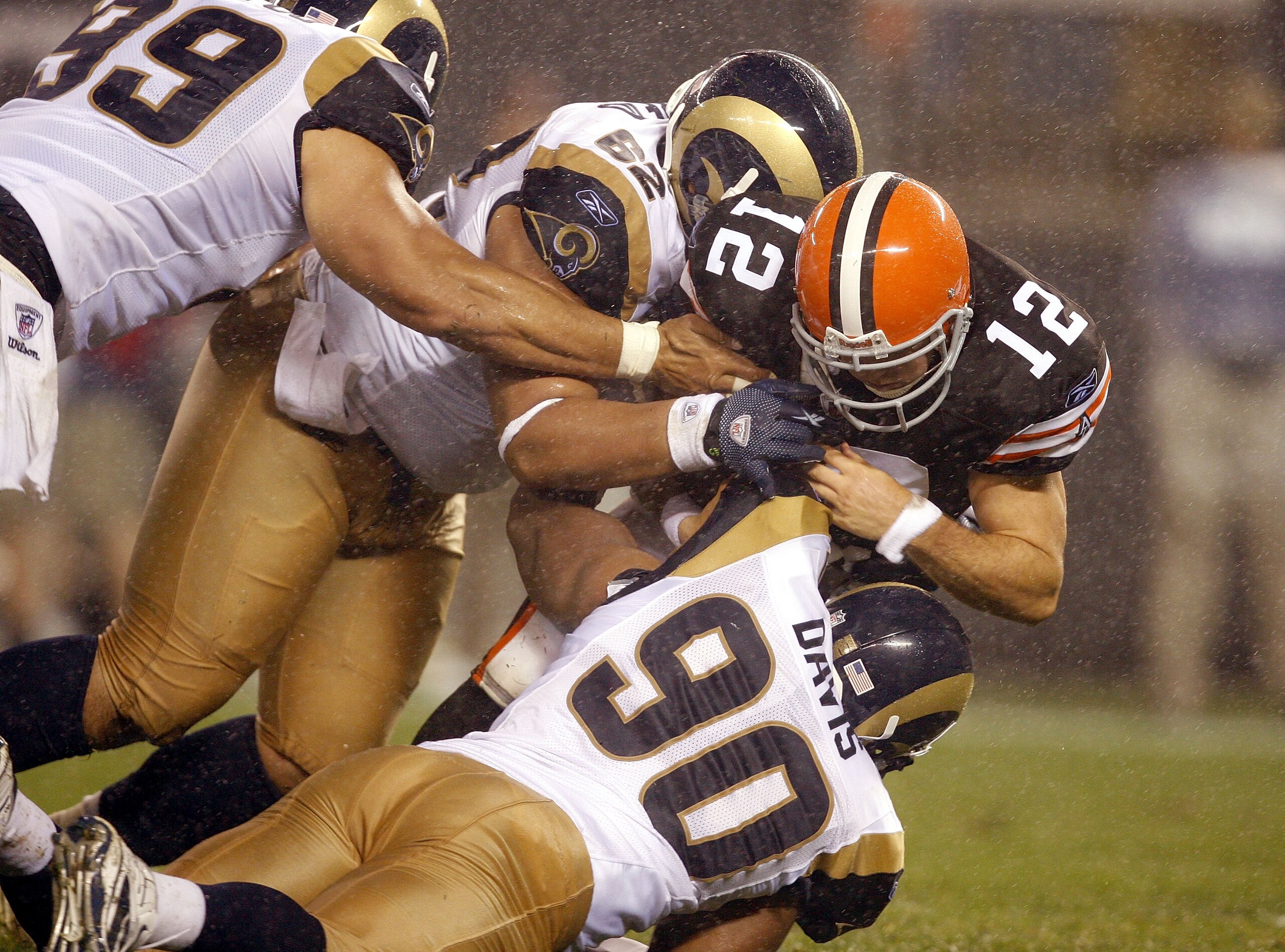 CLEVELAND - AUGUST 21:  C.J. Ah You #99, Ernest Reid #62 and Hall Davis #90 of the St. Louis Rams tackle Colt McCoy #12 of the Cleveland Browns at Cleveland Browns Stadium on August 21, 2010 in Cleveland, Ohio.  (Photo by Matt Sullivan/Getty Images)