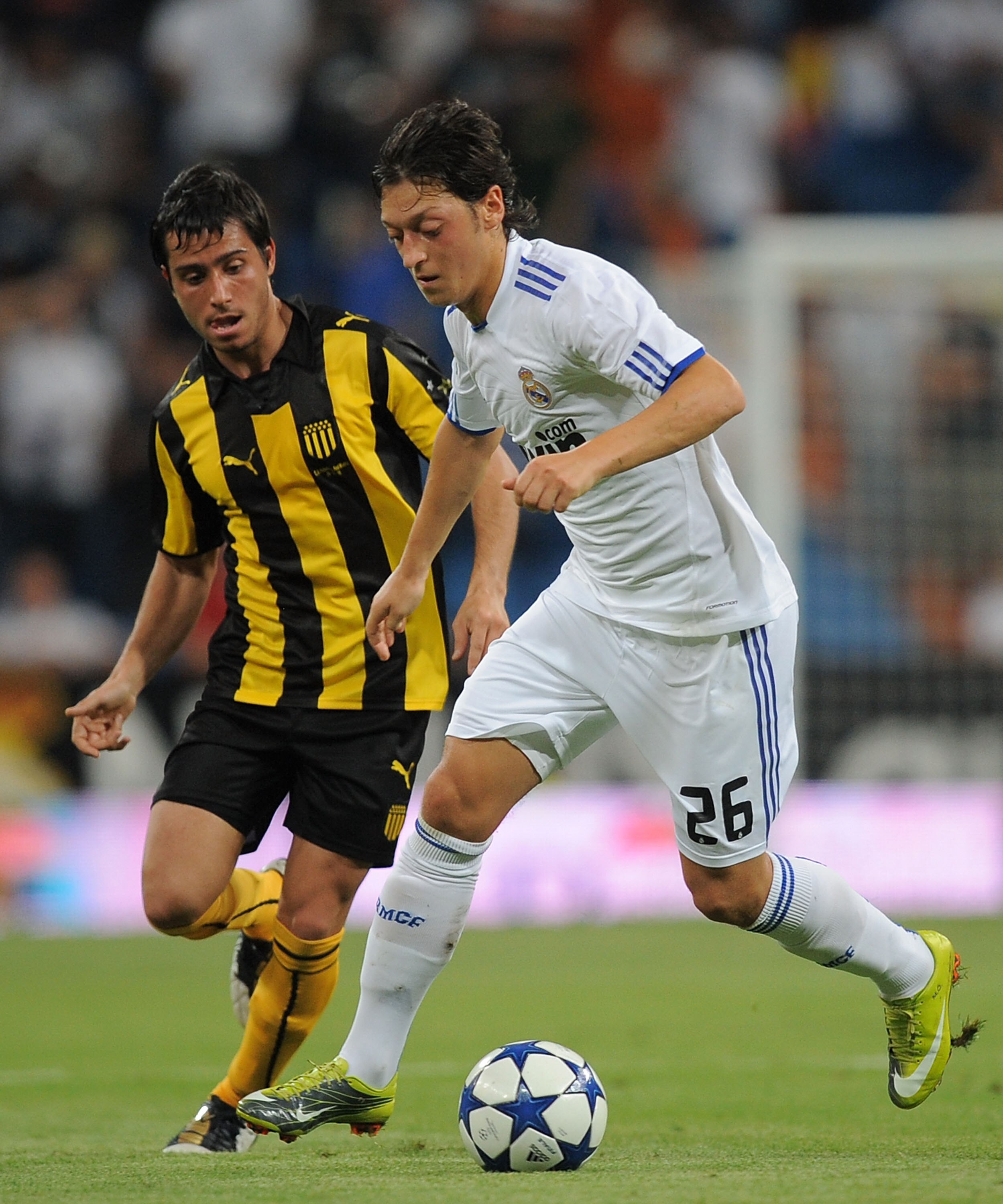 MADRID, SPAIN - AUGUST 24:  Mesut Ozil (R) of Real Madrid is tackled by Pacheco of Penarol during the Santiago Bernabeu Trophy match between Real Madrid and Penarol at the Santiago Bernabeu stadium on August 24, 2010 in Madrid, Spain.  (Photo by Denis Doy
