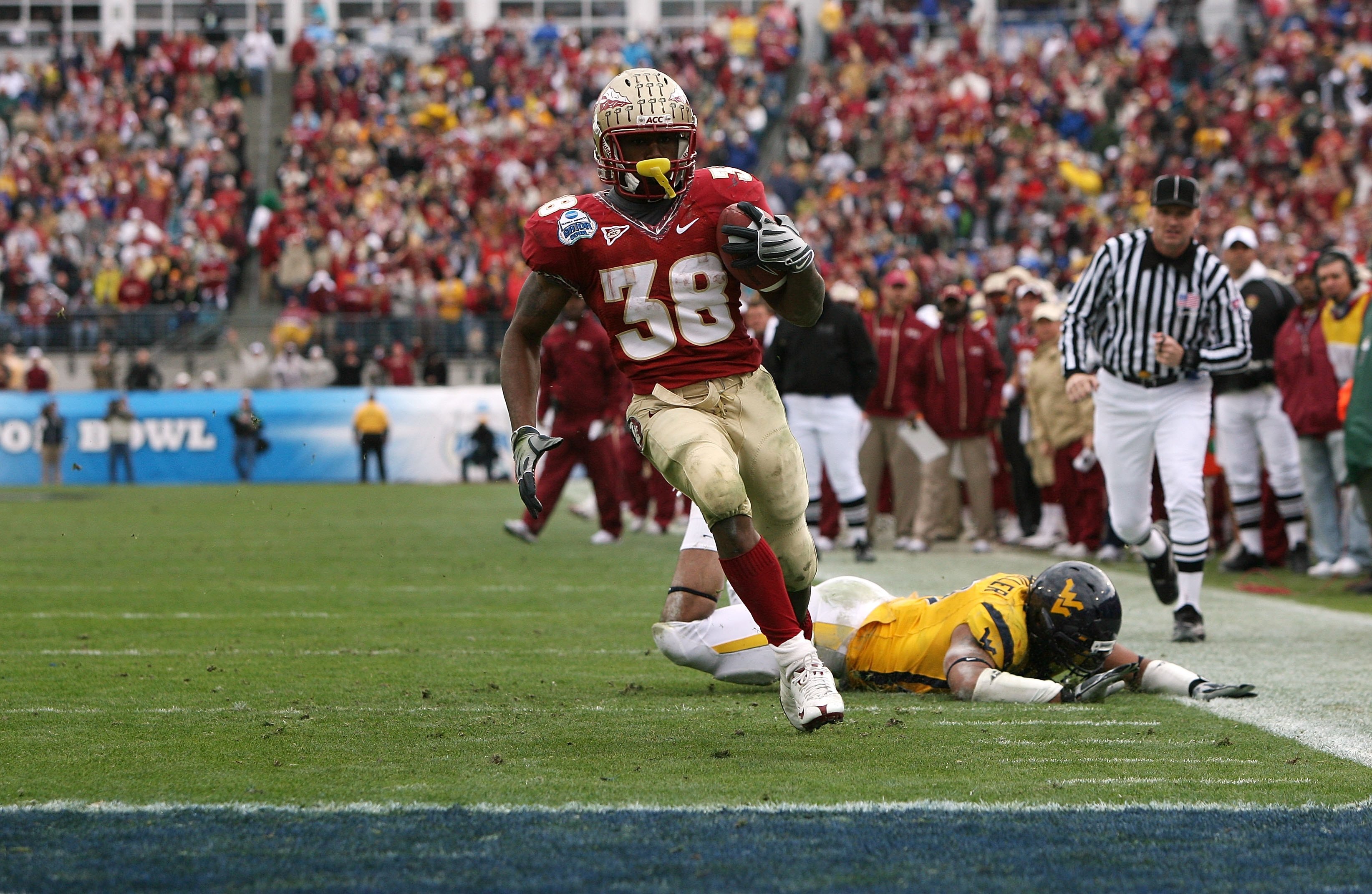 JACKSONVILLE, FL - JANUARY 01:  Running back Jermaine Thomas #38 of the Florida State Seminoles avoids a tackle attempt by linebacker Julian Miller #97 of the West Virginia Mountaineers to score a touchdown in the first quarter during the Konica Minolta G