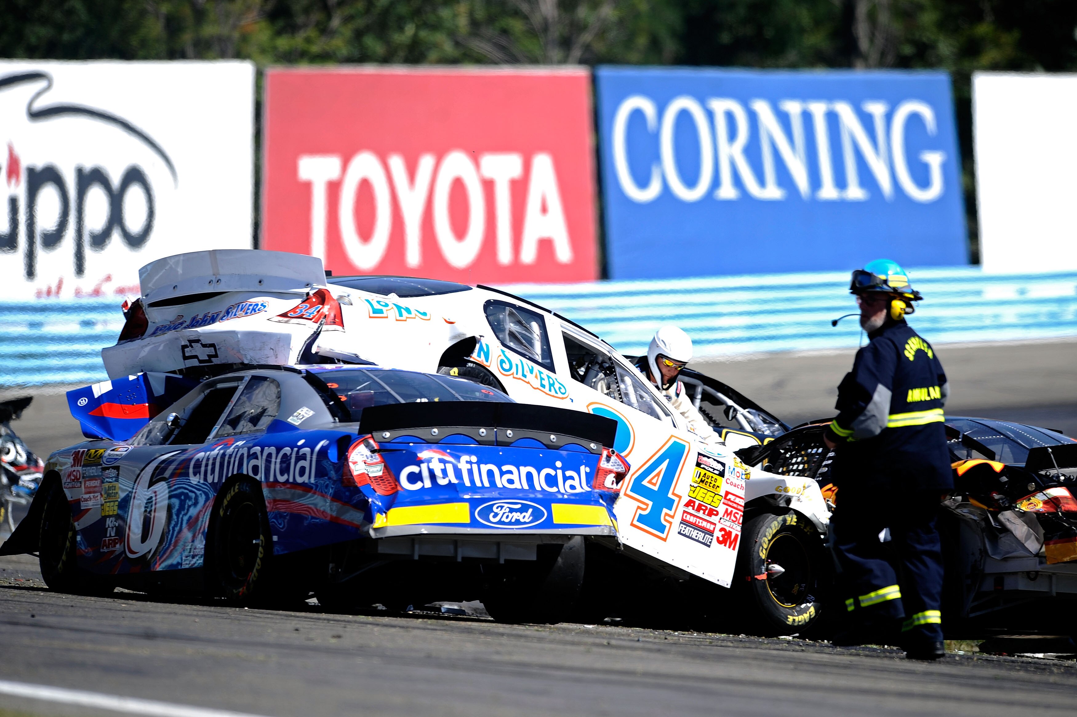 WATKINS GLEN, NY - AUGUST 07:  Safety officials check on Billy Johnson, driver of the #6 CitiFinancial Ford, Tony Raines, driver of the #34 Long John Silver's Chevrolet, and Brendan Gaughan, driver of the #62 South Point Casino & Hotel Toyota, after a cra