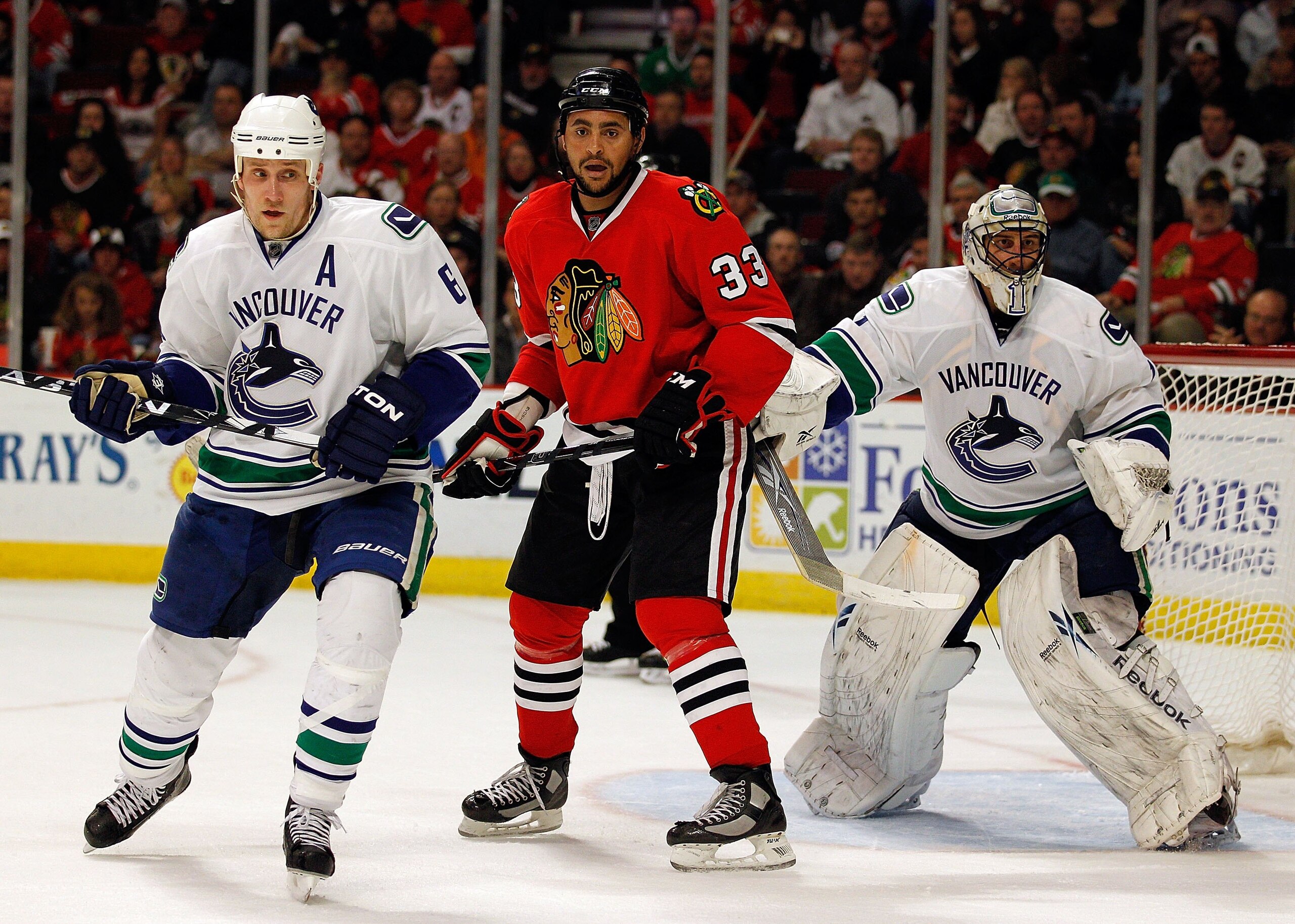 CHICAGO - MAY 09: Dustin Byfuglien #33 of the Chicago Blackhawks places himself between Sami Salo #6 and Roberto Luongo #1 of the Vancouver Canucks in Game Five of the Western Conference Semifinals during the 2010 NHL Stanley Cup Playoffs at United Center
