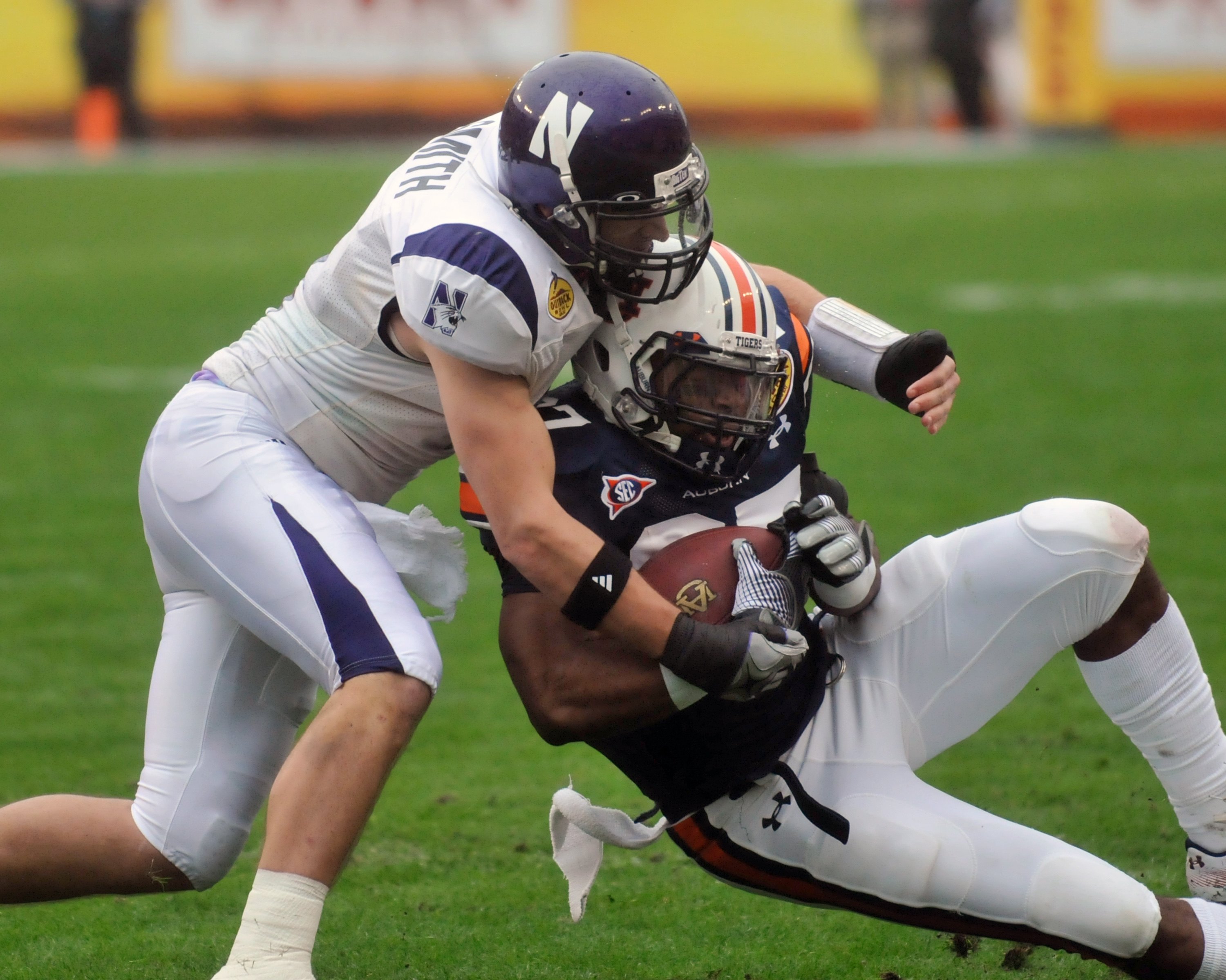 TAMPA, FL - JANUARY 1: Safety Brendan Smith #4 of the Northwestern Wildcats tackles running back Marion Fannin #27 of  the Auburn Tigers in the Outback Bowl January 1, 2010 at Raymond James Stadium in Tampa, Florida.  (Photo by Al Messerschmidt/Getty Imag