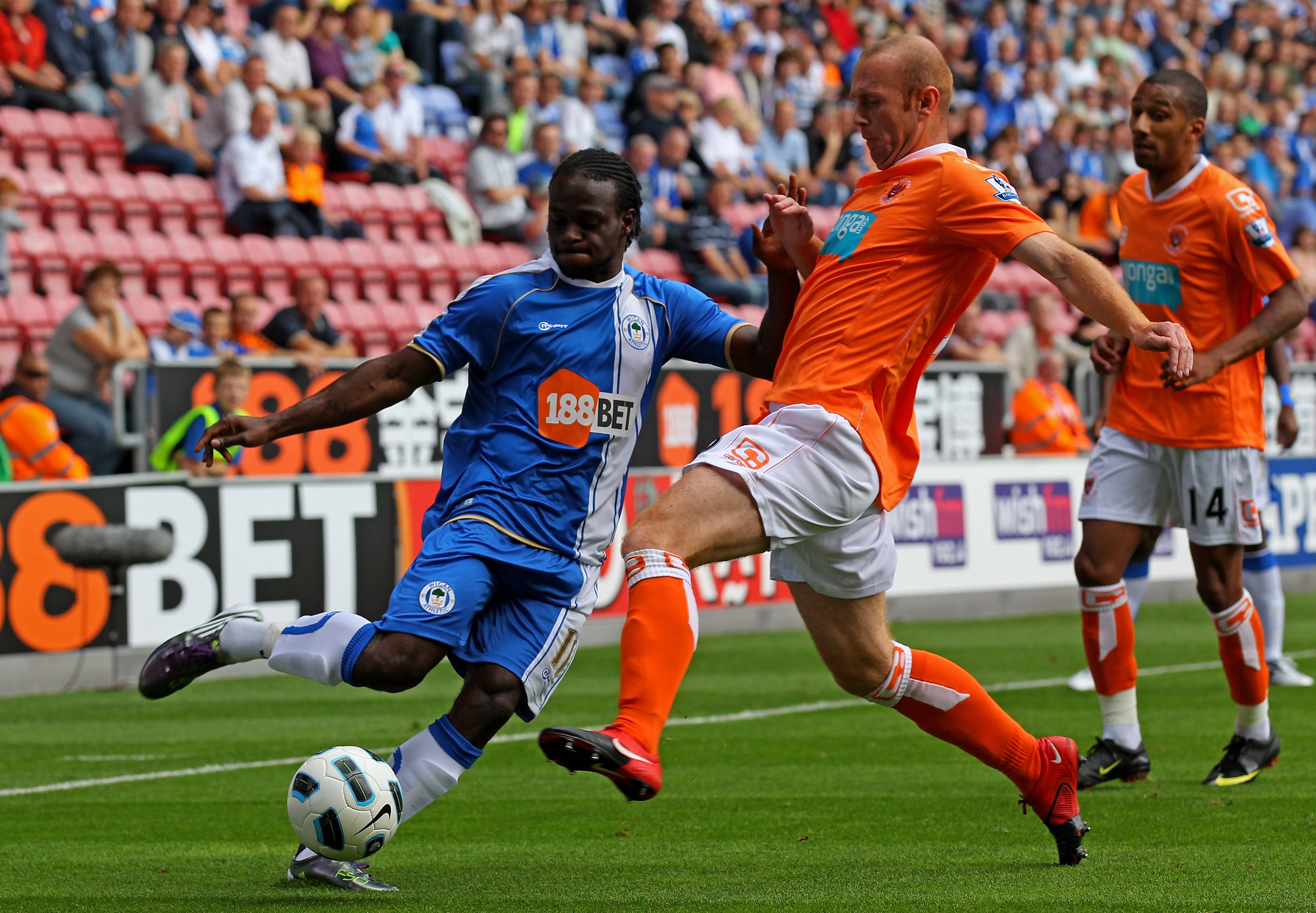 WIGAN, ENGLAND - AUGUST 14:  Victor Moses of Wigan Athletic is challenged by Stephen Crainey of Blackpool during the Barclays Premier League match between Wigan Athletic and Blackpool at the DW Stadium on August 14, 2010 in Wigan, England. (Photo by Alex 