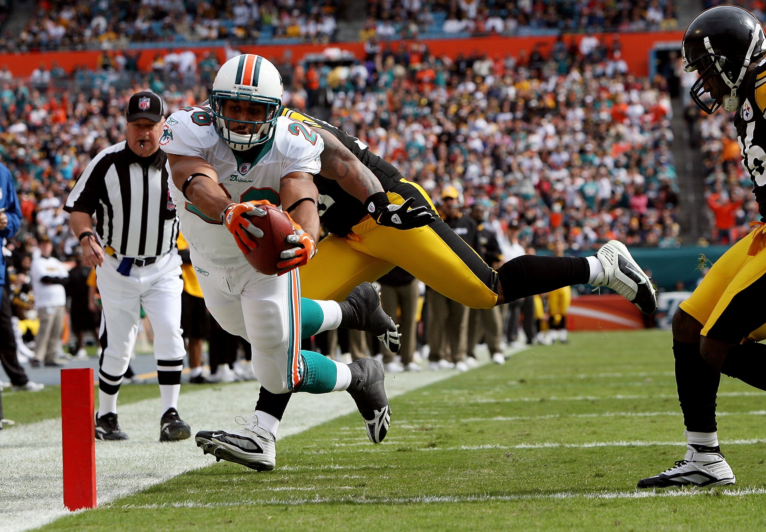 MIAMI - JANUARY 03:  Running back Lex Hilliard #26 of the Miami Dolphins dives for a touchdown past linebacker LaMarr Woodley #56 and Deshea Townsend #26 of the Pittsburgh Steelers at Land Shark Stadium on January 3, 2010 in Miami, Florida.  (Photo by Dou