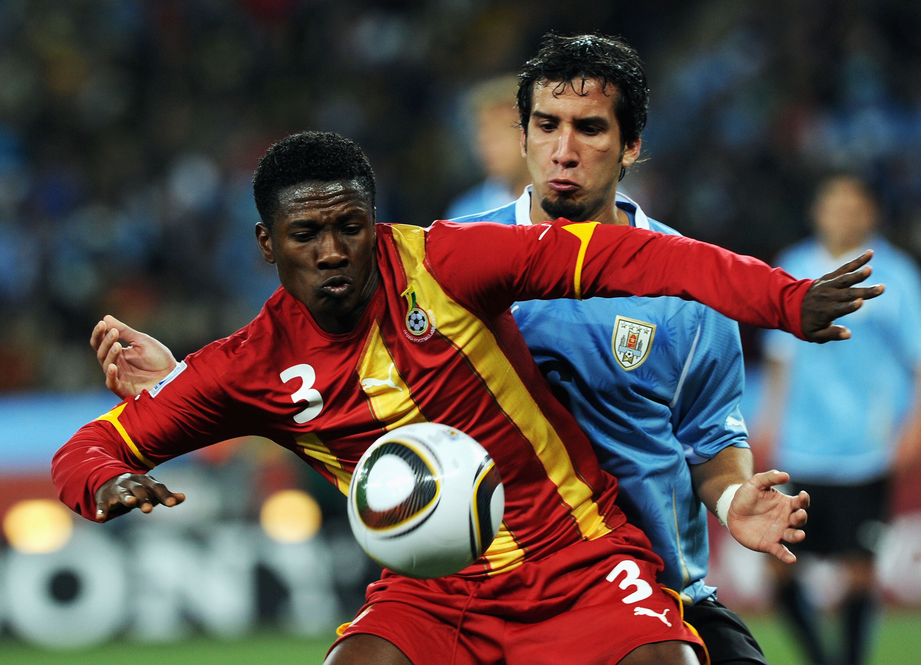 JOHANNESBURG, SOUTH AFRICA - JULY 02:  Jorge Fucile of Uruguay watches Asamoah Gyan of Ghana during the 2010 FIFA World Cup South Africa Quarter Final match between Uruguay and Ghana at the Soccer City stadium on July 2, 2010 in Johannesburg, South Africa