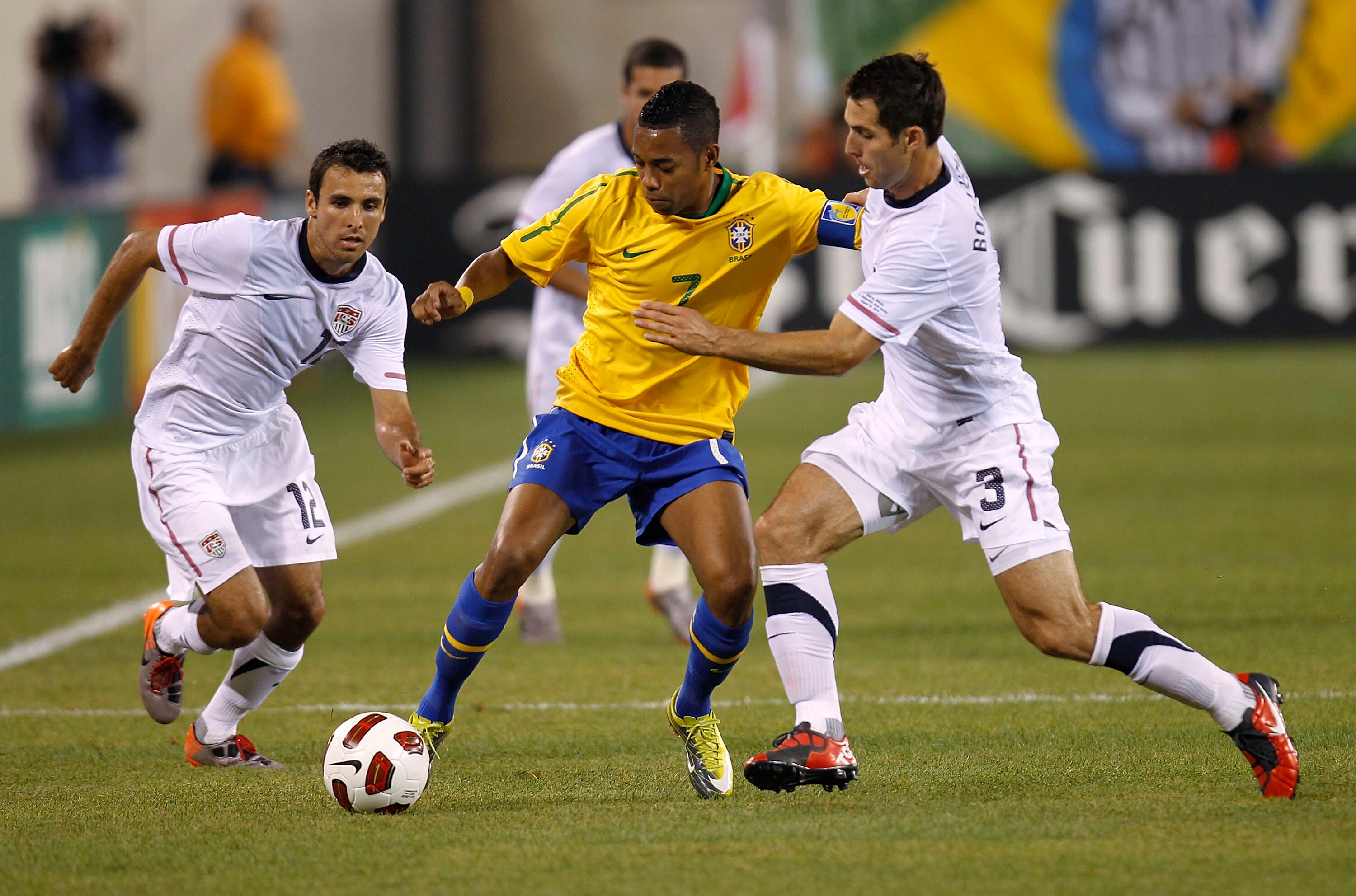 EAST RUTHERFORD, NJ - AUGUST 10: Jonathan Bornstein #12 and Carlos Bocanegra #3 of the U.S. guard Robinho #7 of Brazil in the first half of a friendly match at the New Meadowlands on August 10, 2010 in East Rutherford, New Jersey.  (Photo by Jeff Zelevans