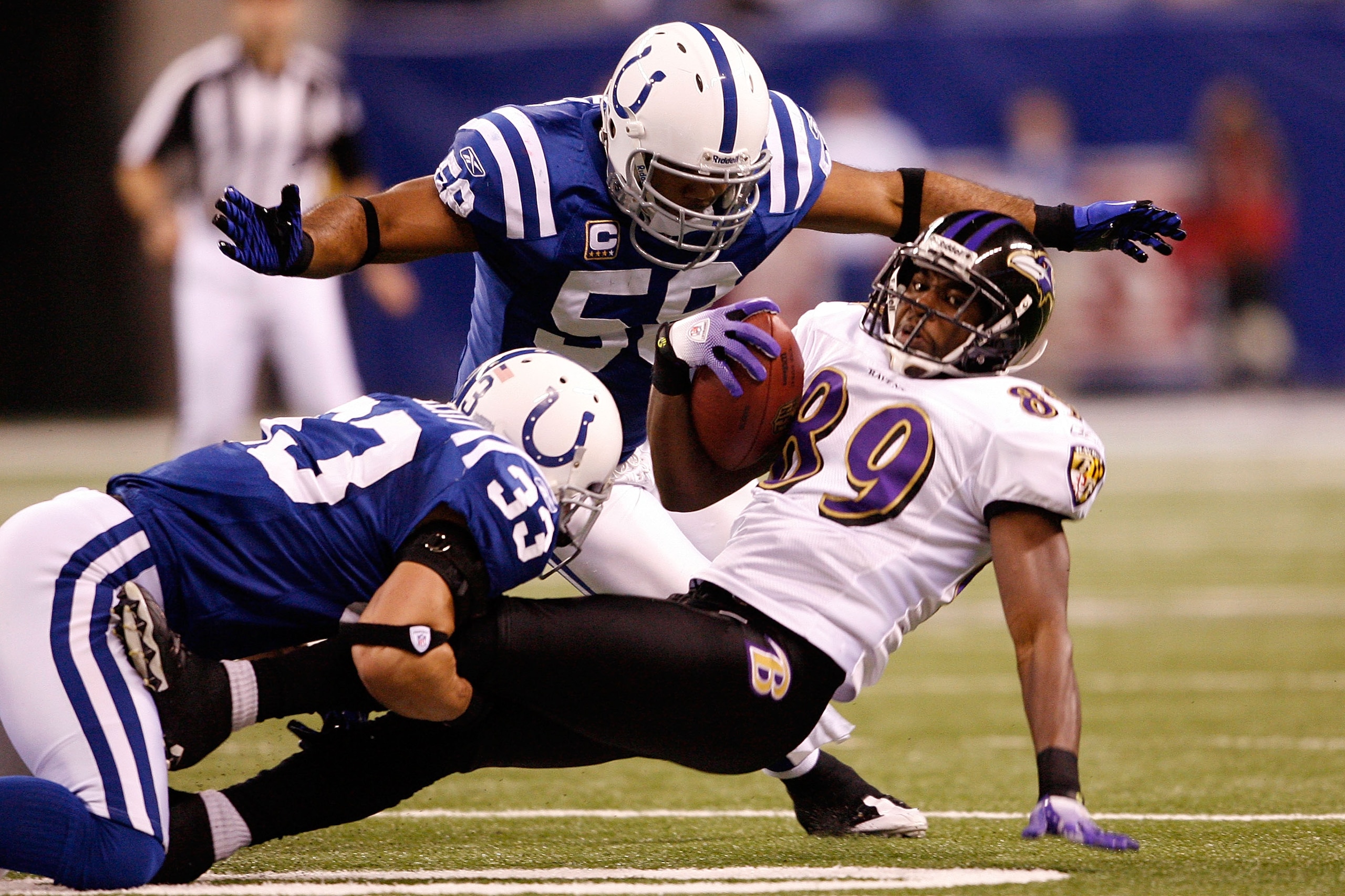 INDIANAPOLIS - JANUARY 16:  Mark Clayton #89 of the Baltimore Ravens is tackled by Melvin Bullitt #33 and Philip Wheeler #50 of the Indianapolis Colts after a catch in the first quarter of the AFC Divisional Playoff Game at Lucas Oli Stadium on January 16