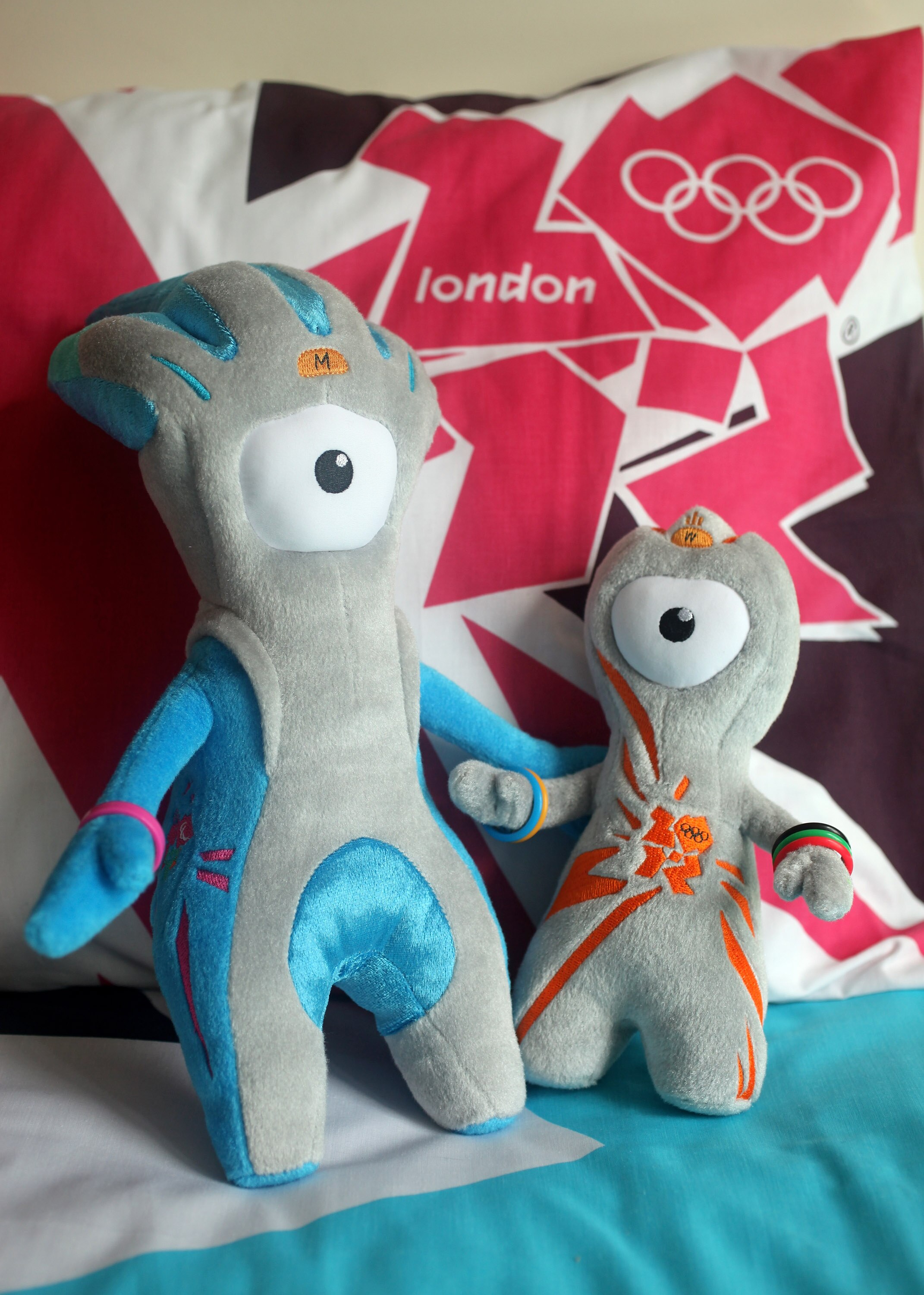 LONDON, ENGLAND - JULY 30:  Wenlock (R) and Mandeville (L), soft toy mascots for the London 2012 Olympic Games, are placed on a London 2012 bedspread at the launch of the London Olympic Games official merchandise on July 30, 2010 in London, England. The m