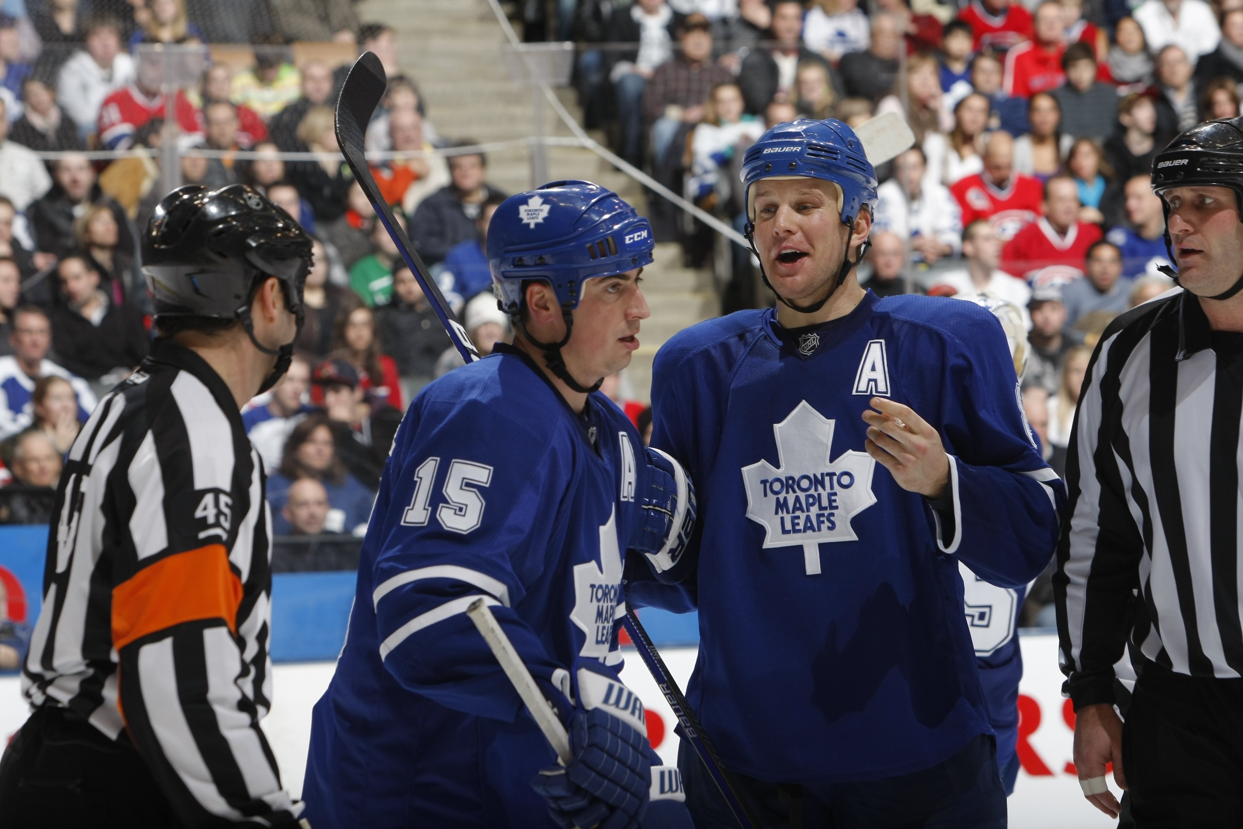 TORONTO - DECEMBER 26:  Mike Komisarek #8 of the Toronto Maple Leafs has a word for NHL referee Justin St. Pierre during a break in NHL game action between the Montreal Canadiens and the Toronto Maple Leafs at the Air Canada Centre on December 26, 2009 in