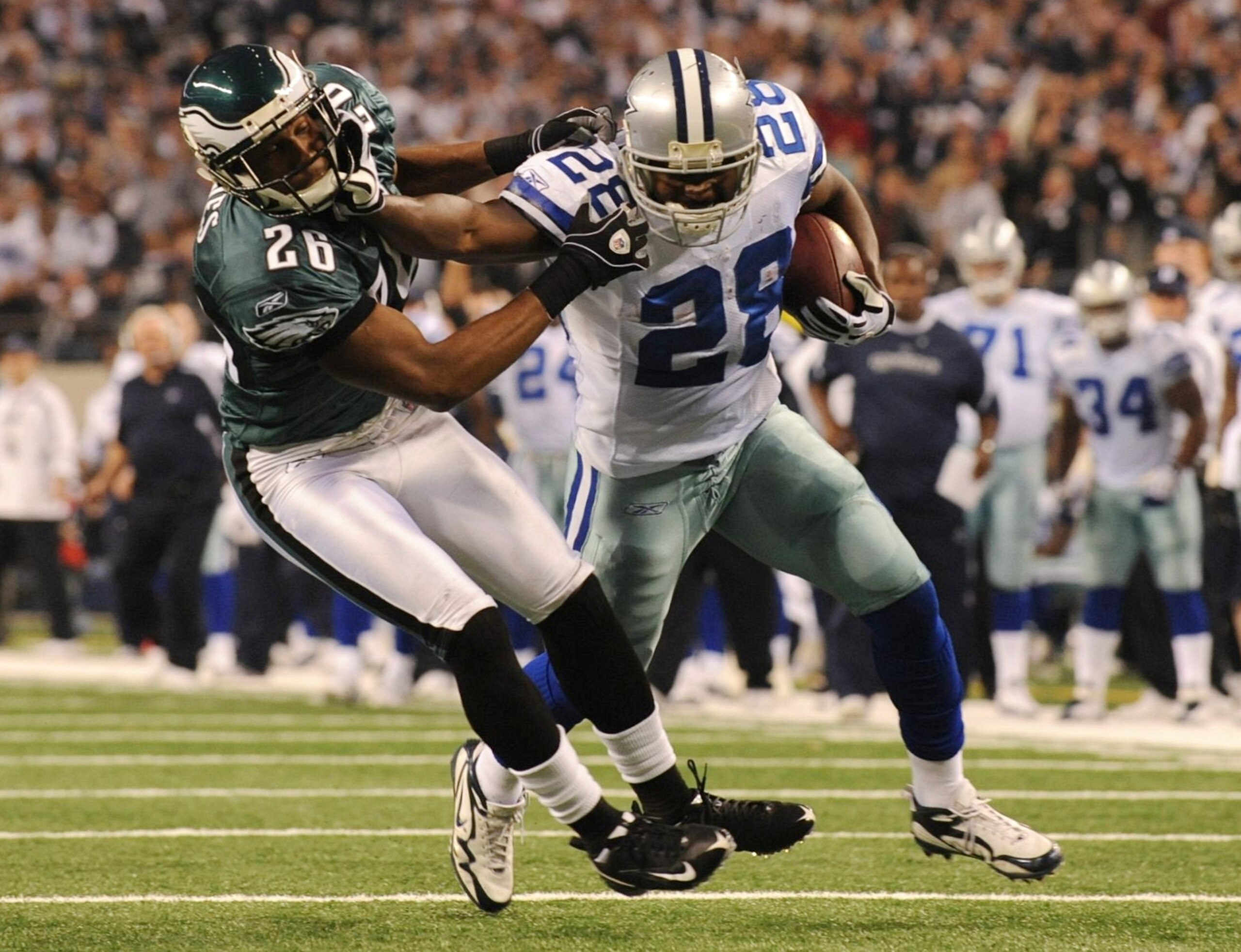 ARLINGTON, TX - JANUARY 9:  Running back Felix Jones #28 of the Dallas Cowboys stiff arms safety Sean Jones #26 of the Philadelphia Eagles during the 2010 NFC wild-card playoff game at Cowboys Stadium on January 9, 2010 in Arlington, Texas. (Photo by Rona
