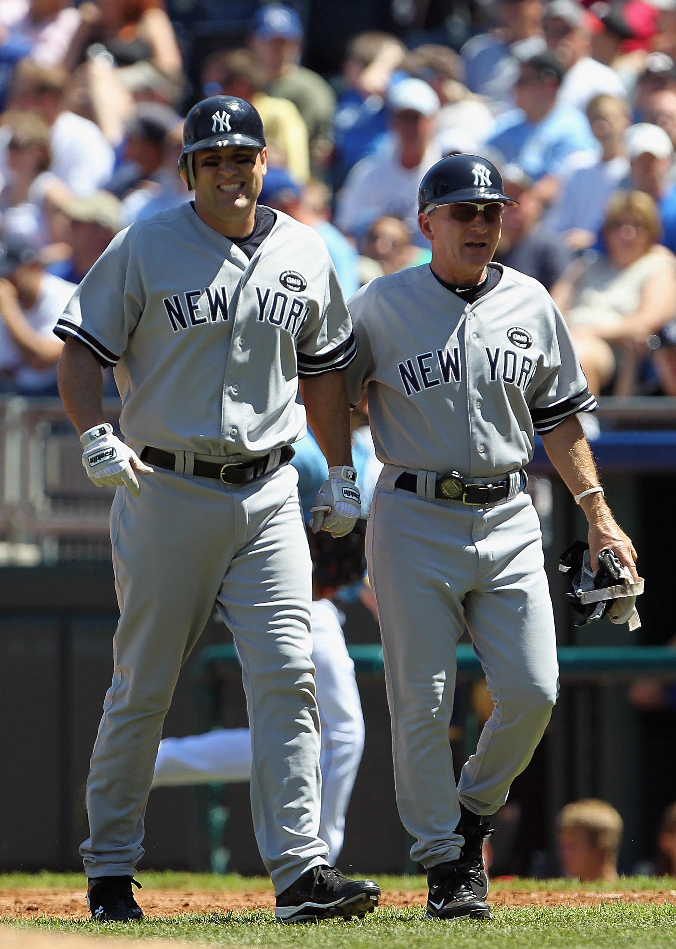 KANSAS CITY, MO - AUGUST 15:  First base coach Mick Kelleher #50 of the New York Yankees helps off Lance Berkman #17 after Berkman sufferend an injury during the game against the Kansas City Royals on August 15, 2010 at Kauffman stadium in Kansas City, Mi