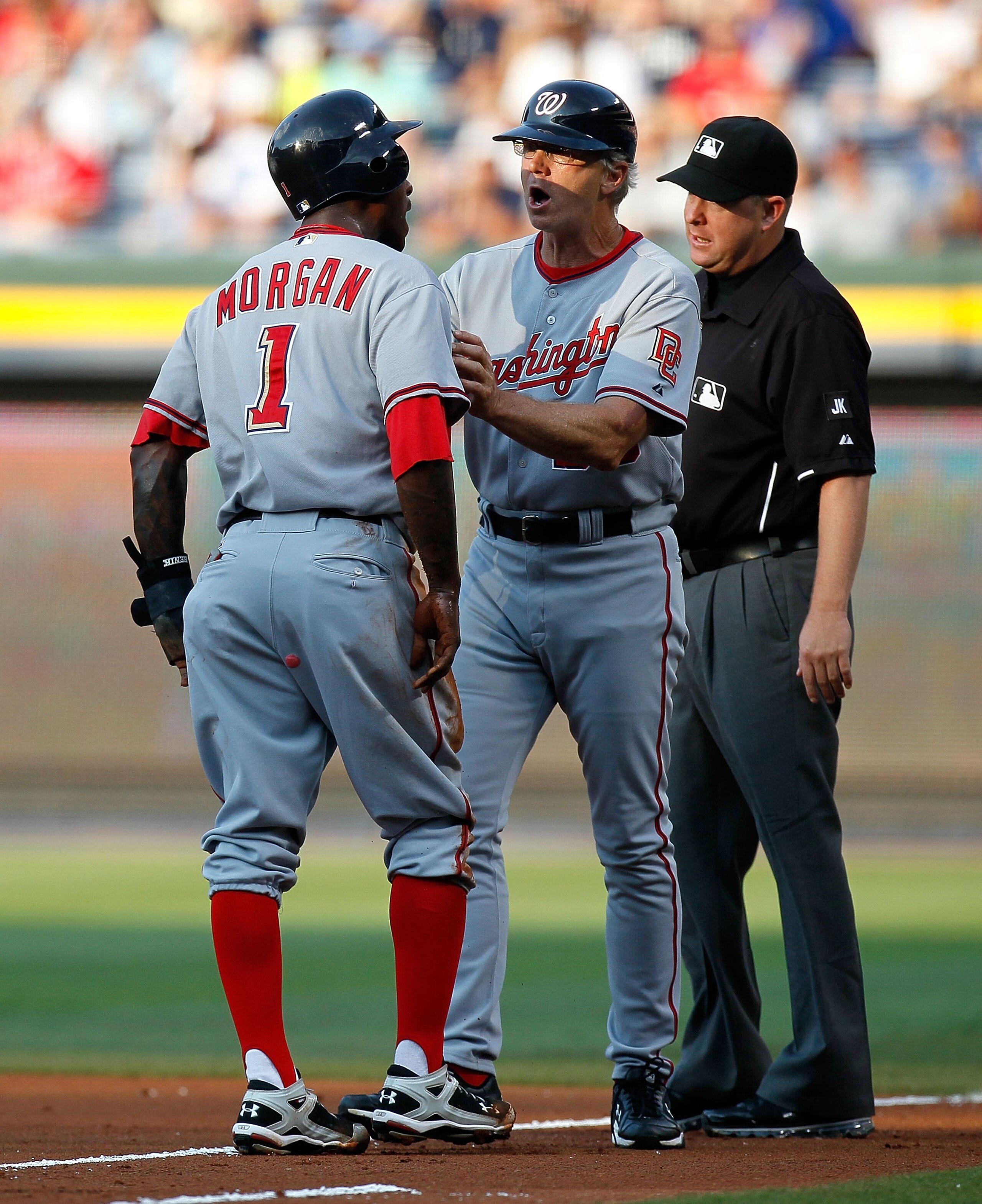 ATLANTA - JUNE 28:  Dan Radison #53 of the Washington Nationals holds back Nyjer Morgan #1 in the first inning from arguing with first base umpire James Hoye #92 (right) after being tagged out at first base against the Atlanta Braves at Turner Field on Ju