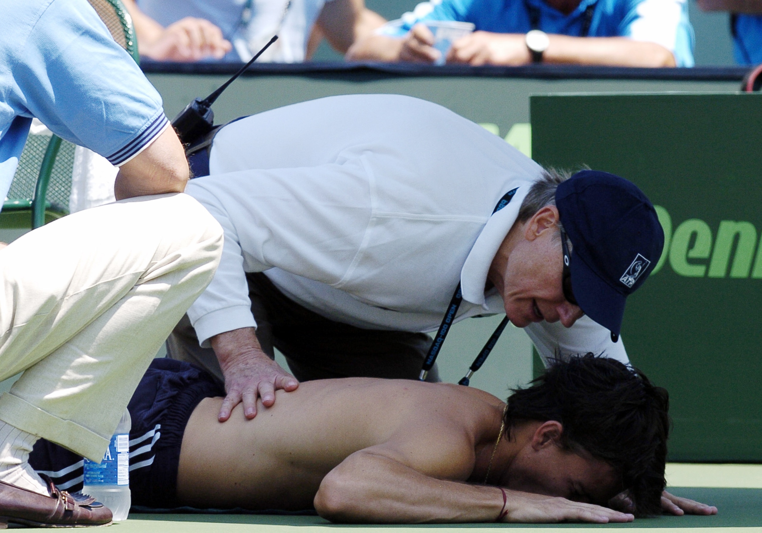Guillermo Coria  receives treatment from ATP trainer  Bill Norris  then retires after a back injury during the   men's singles match at  the NASDAQ 100 Open, April 4, 2004, Key Biscayne, Florida. (Photo by A. Messerschmidt/Getty Images)