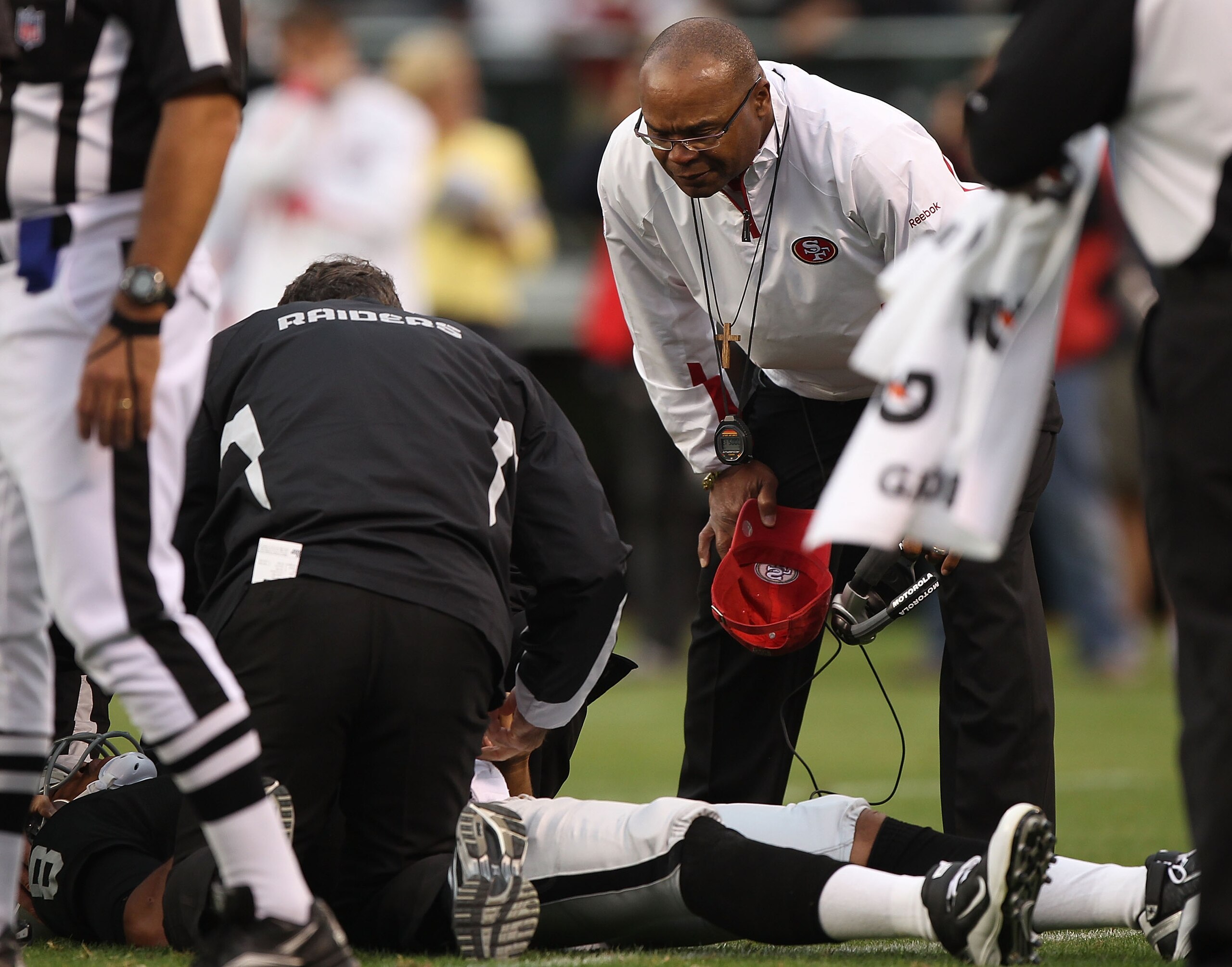 OAKLAND, CA - AUGUST 28: Jason Campbell #8 of the Oakland Raiders lies on the ground injured as head coach Mike Singletary of the San Francisco 49ers looks on during an NFL preseason game at Oakland-Alameda County Coliseum on August 28, 2010 in Oakland, C