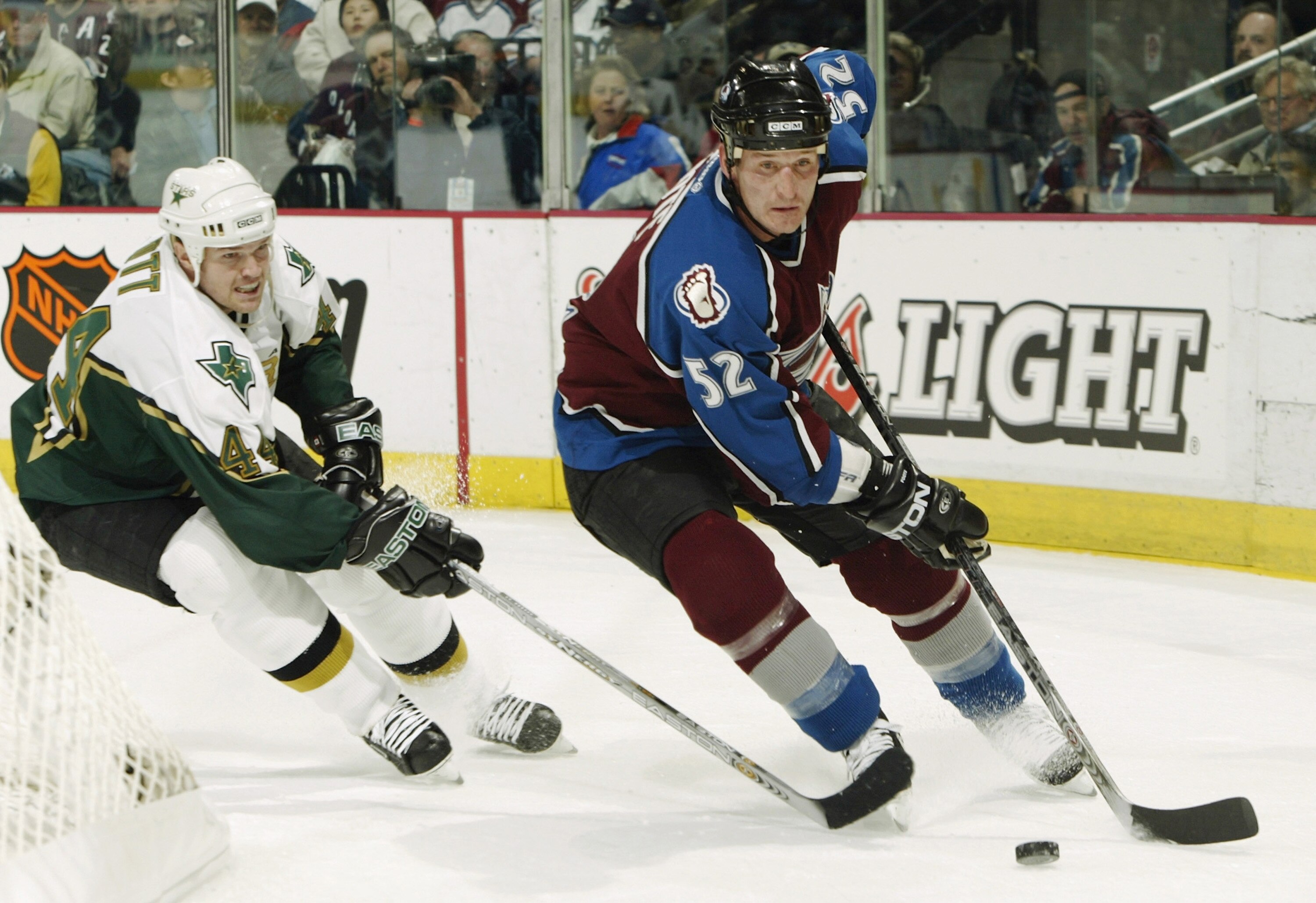 DENVER - APRIL 7:  Adam Foote #52 of the Colorado Avalanche takes the puck around the back of his own net under pursuit from Jason Arnott #44 of the Dallas Stars in the second period during the first round of the Stanley Cup playoffs at the Pepsi Center o