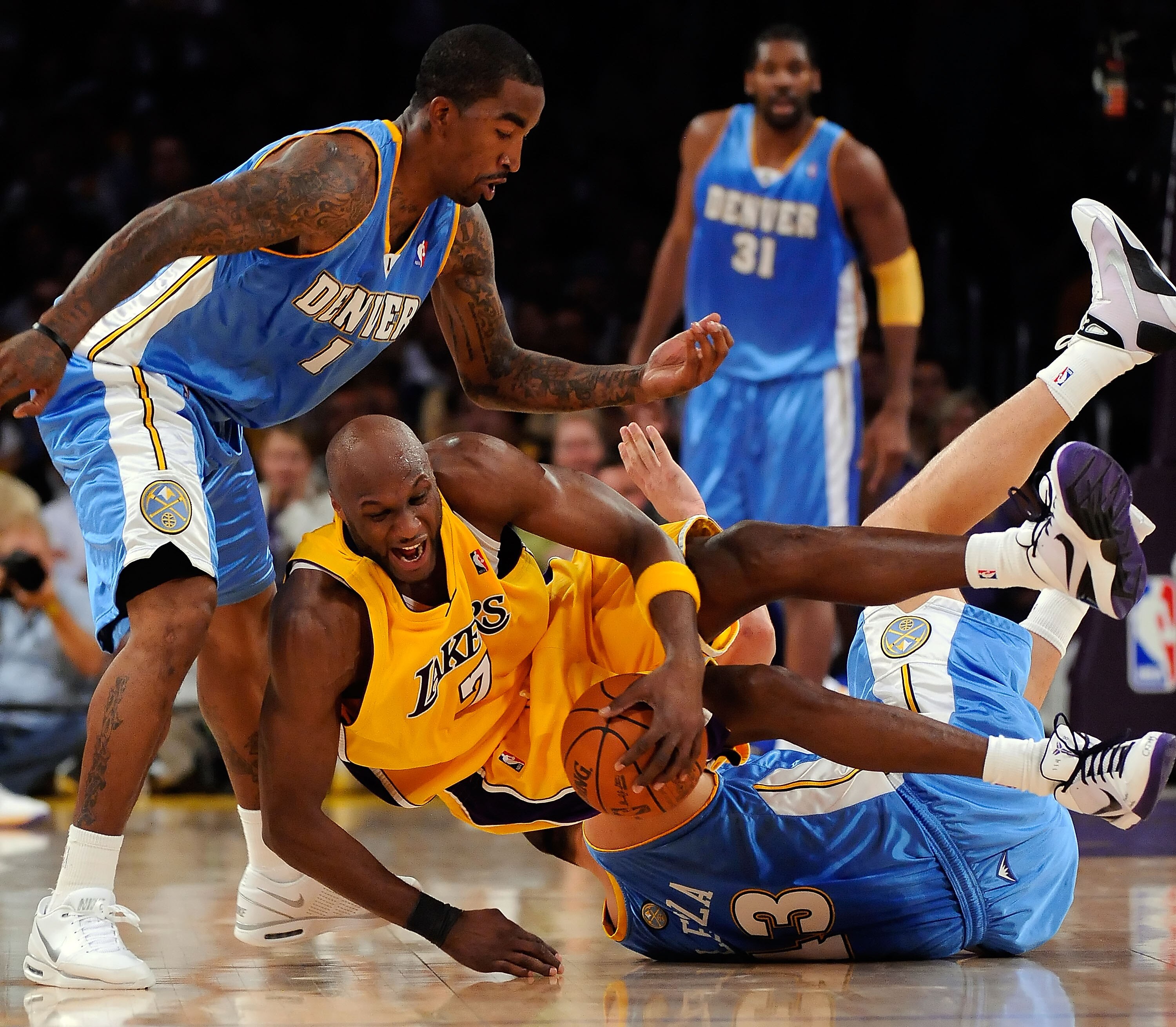 LOS ANGELES, CA - MAY 27:  Lamar Odom #7 of the Los Angeles Lakers grabs the ball as he rolls over Linas Kleiza #43 of the Denver Nuggets as J.R. Smith #1 of the Nuggets goes for the ball in the fourth quarter of Game Five of the Western Conference Finals