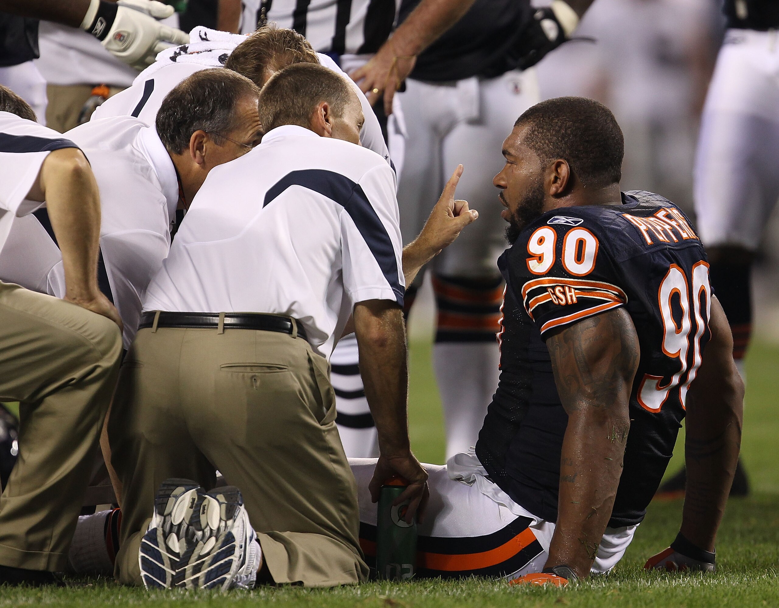 CHICAGO - AUGUST 21: Julius Peppers #90 of the Chicago Bears is attended to by trainers after an injury against the Oakland Raiders during a preseason game at Soldier Field on August 21, 2010 in Chicago, Illinois. The Radiers defeated the Bears 32-17. (Ph