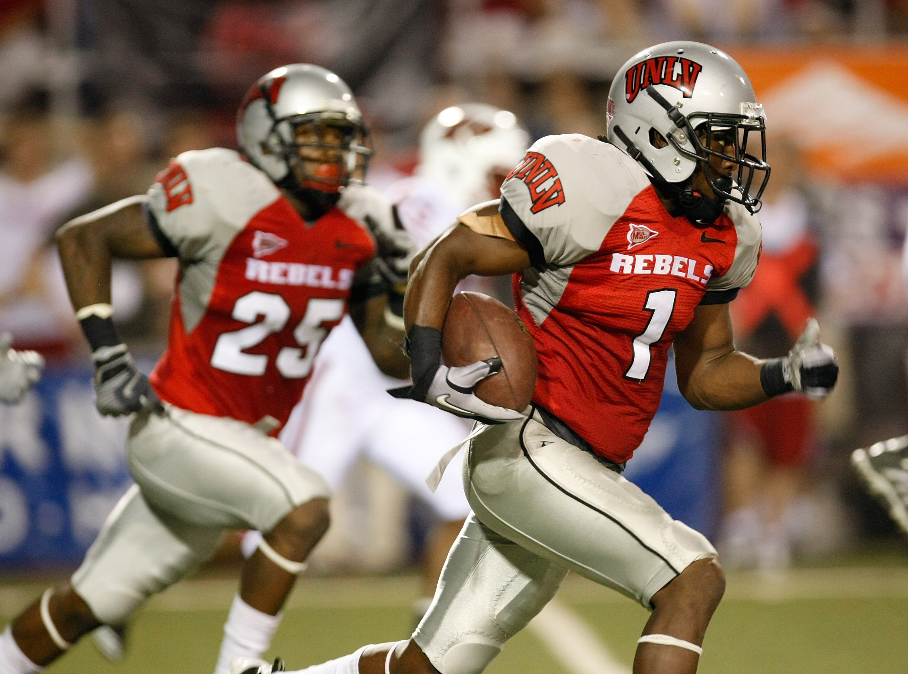 LAS VEGAS - SEPTEMBER 04:  Will Chandler #1 of the UNLV Rebels runs for yardage after recovering a fumble during the second quarter of their game against the Wisconsin Badgers at Sam Boyd Stadium September 4, 2010 in Las Vegas, Nevada. Mike Grant #25 of U