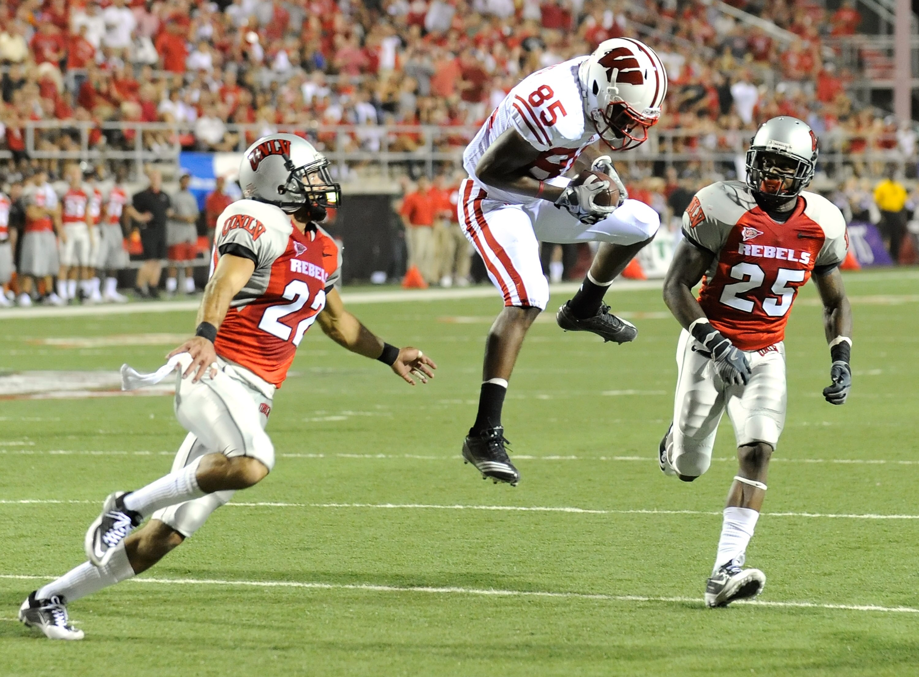 LAS VEGAS - SEPTEMBER 04:  David Gilreath #85 of the Wisconsin Badgers catches a pass between Alex De Giacomo #22 and #25 Mike Grant of the UNLV Rebels during the first quarter of their game at Sam Boyd Stadium September 4, 2010 in Las Vegas, Nevada.  (Ph