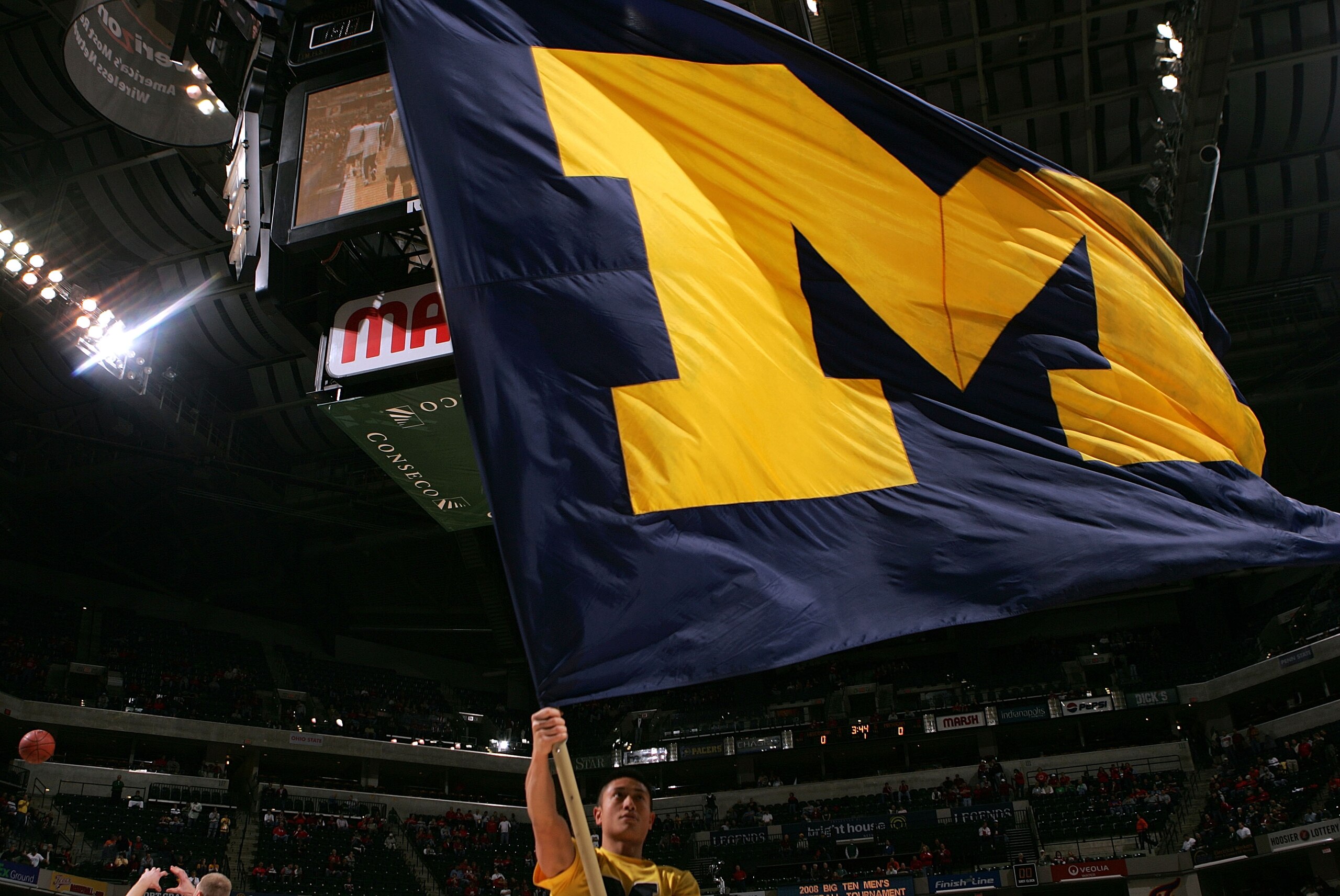 INDIANAPOLIS - MARCH 14:  A cheerleader from the Michigan Wolverines waves a flag in support of his team against the Wisconsin Badgers  during the Big Ten Men's Basketball Tournament at Conseco Fieldhouse on March 14, 2008 in Indianapolis, Indiana.  (Phot