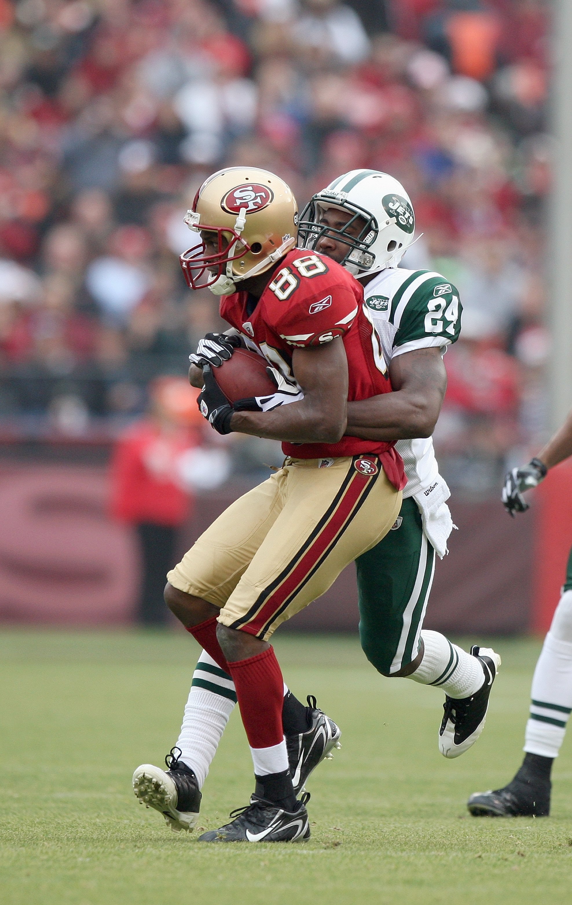SAN FRANCISCO - DECEMBER 07:  Isaac Bruce #88 of the San Francisco 49ers grips the ball as she is tackled by Darrelle Revis #24 of the New York Jets during an NFL game on December 7, 2008 at Candlestick Park in San Francisco, California. (Photo by Jed Jac