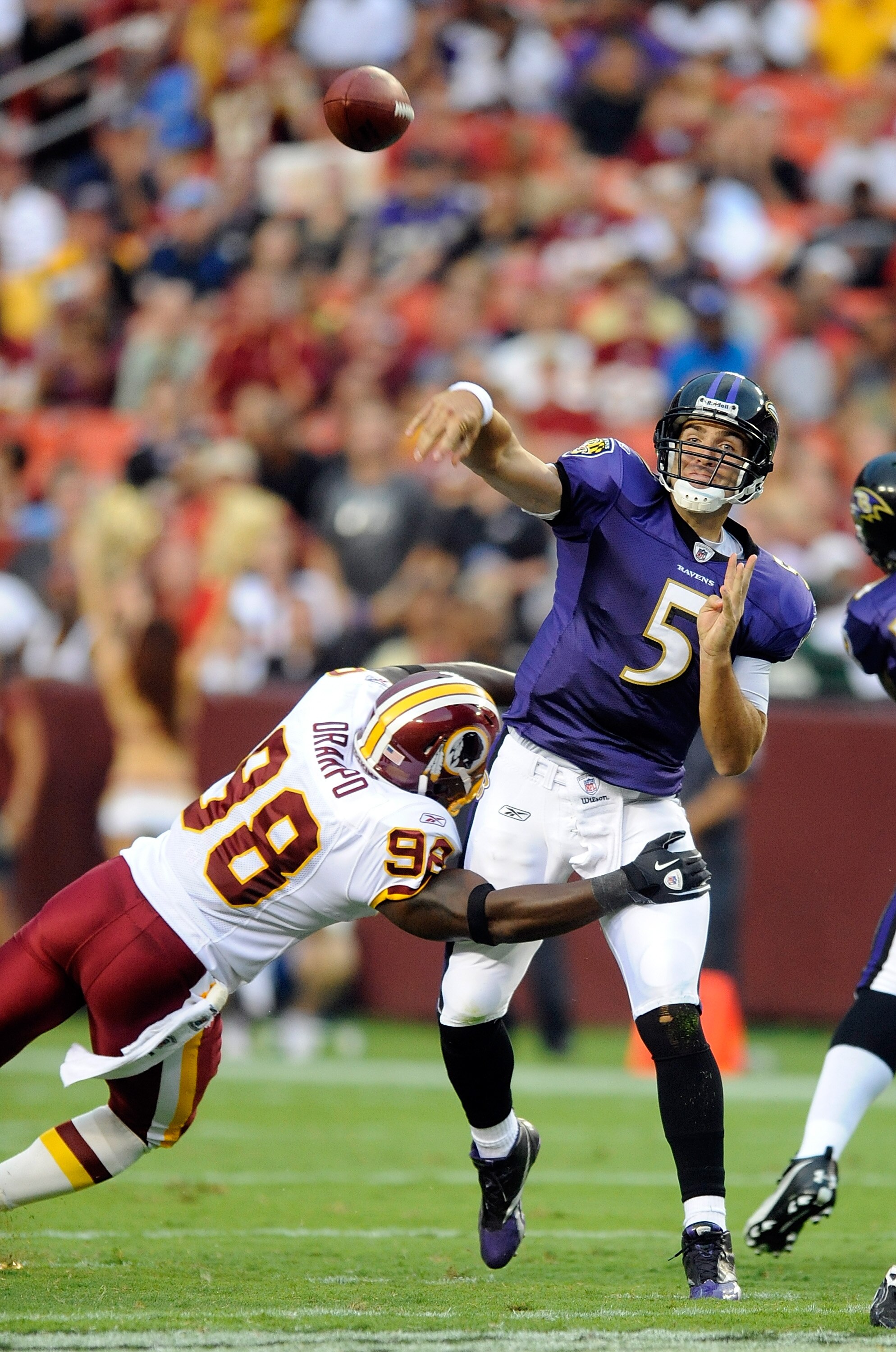 LANDOVER, MD - AUGUST 21:  Joe Flacco #5 of the Baltimore Ravens throws a pass during the preseason game as he is hit by Brian Orakpo #98 of the Washington Redskins at FedExField on August 21, 2010 in Landover, Maryland.  (Photo by Greg Fiume/Getty Images