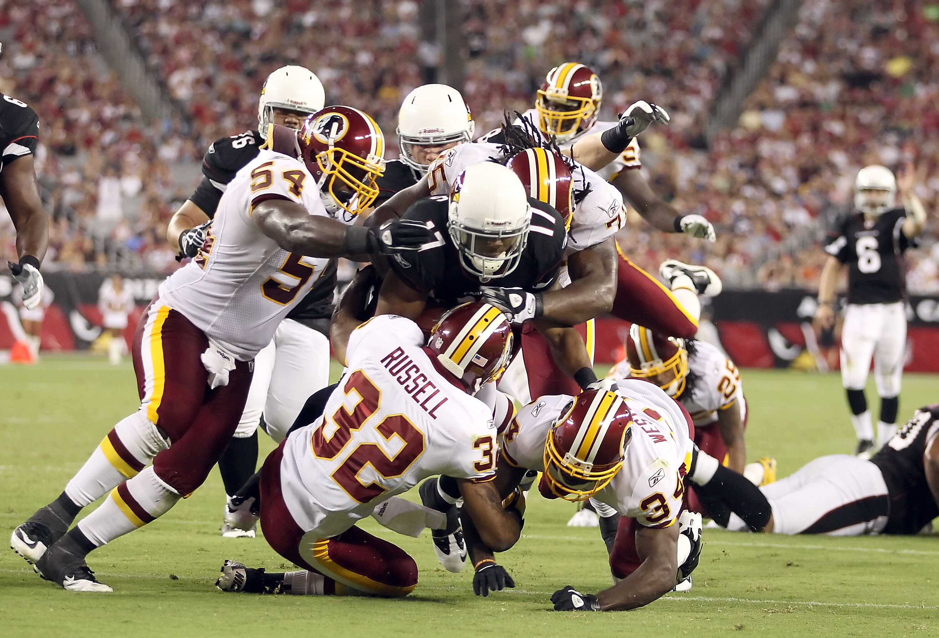 GLENDALE, AZ - SEPTEMBER 02:  Wide receiver Onrea Jones #17 of the Arizona Cardinals is tackled by H.B. Blades #54, Anderson Russell #32 and Byron Westbrook #34  of the Washington Redskins after a 16 yard reception during the second quarter of the preseas