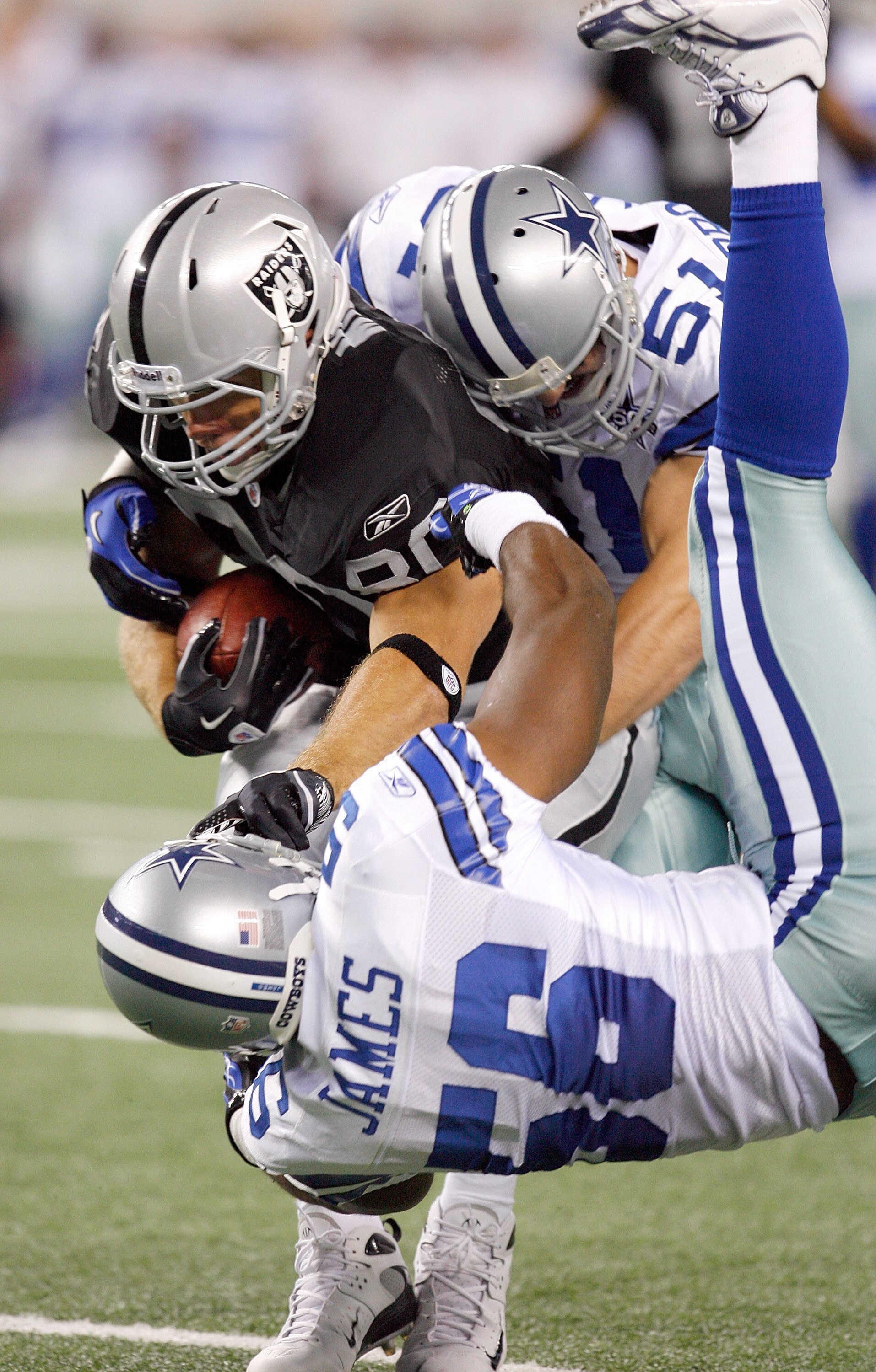 ARLINGTON, TX - AUGUST 12:  Zach Miller #80 of the Oakland Raiders carries the ball against Bradie James #56 and Keith Brooking #51 of the Dallas Cowboys during the preseason game at Dallas Cowboys Stadium on August 12, 2010 in Arlington, Texas.  (Photo b