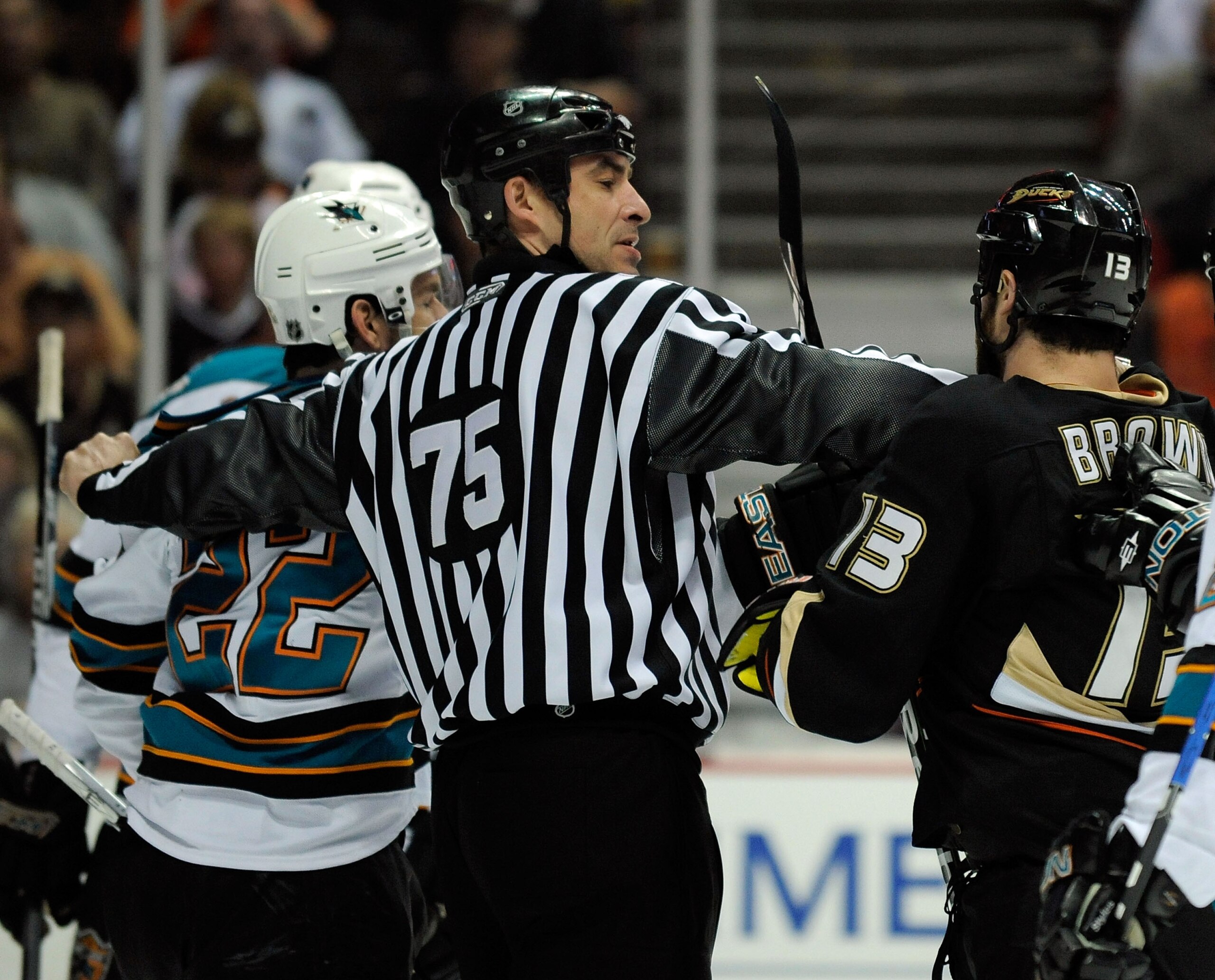 ANAHEIM, CA - APRIL 23:   Linesman Derek Amell #75 separates Mike Brown #13 of the Anaheim Ducks from Dan Boyle #22 of the San Jose Sharks in the first period during Game Four of the Western Conference Quarterfinal Round of the 2009 Stanley Cup Playoffs a