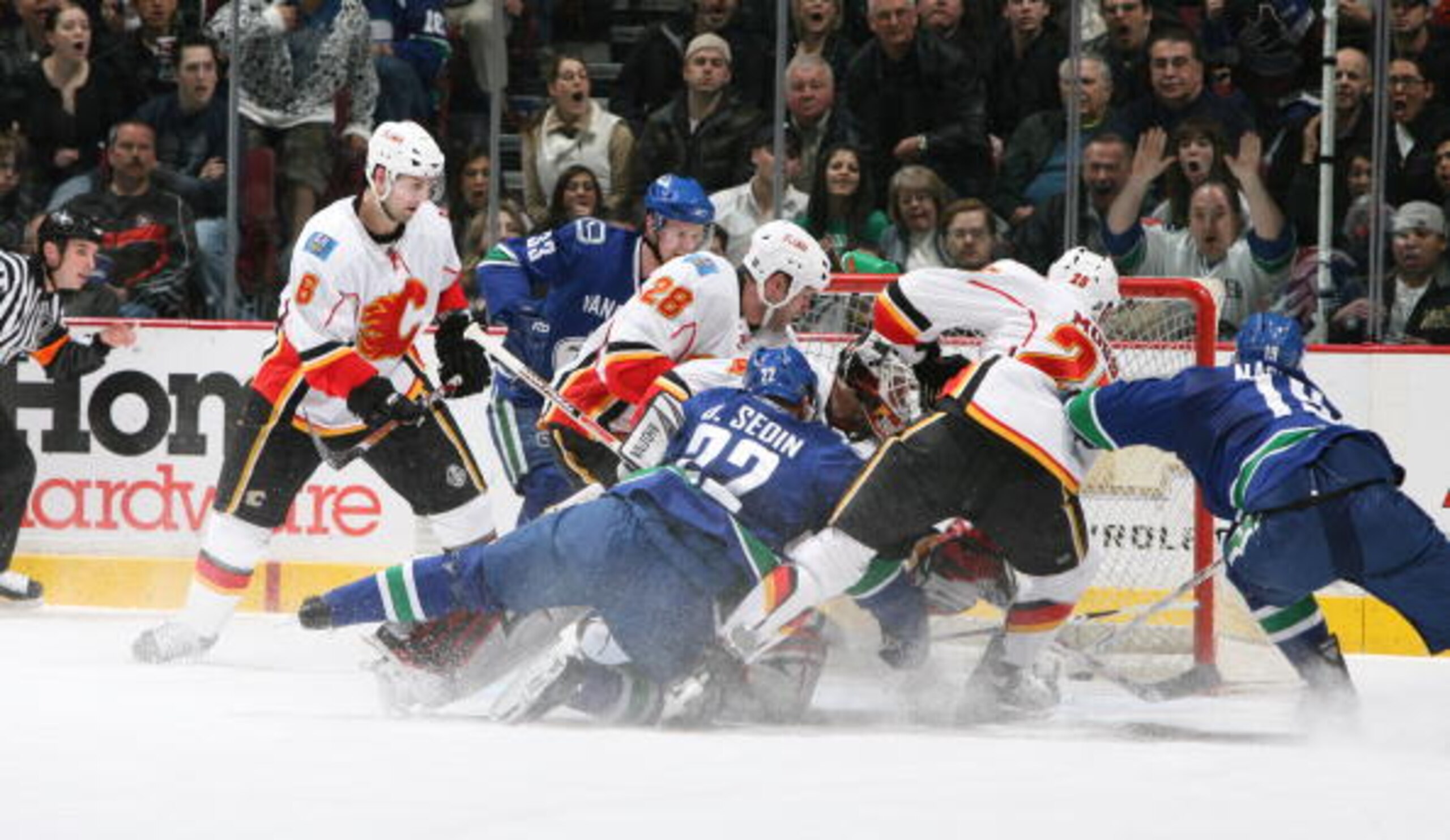 VANCOUVER, CANADA - MARCH 30:  Markus Naslund #19 of the Vancouver Canucks sneaks the puck past Miikka Kiprusoff #34 of the Calgary Flames  following Daniel Sedin #22 of the Vancouver Canucks as he moves to the crease during the game at General Motors Pla