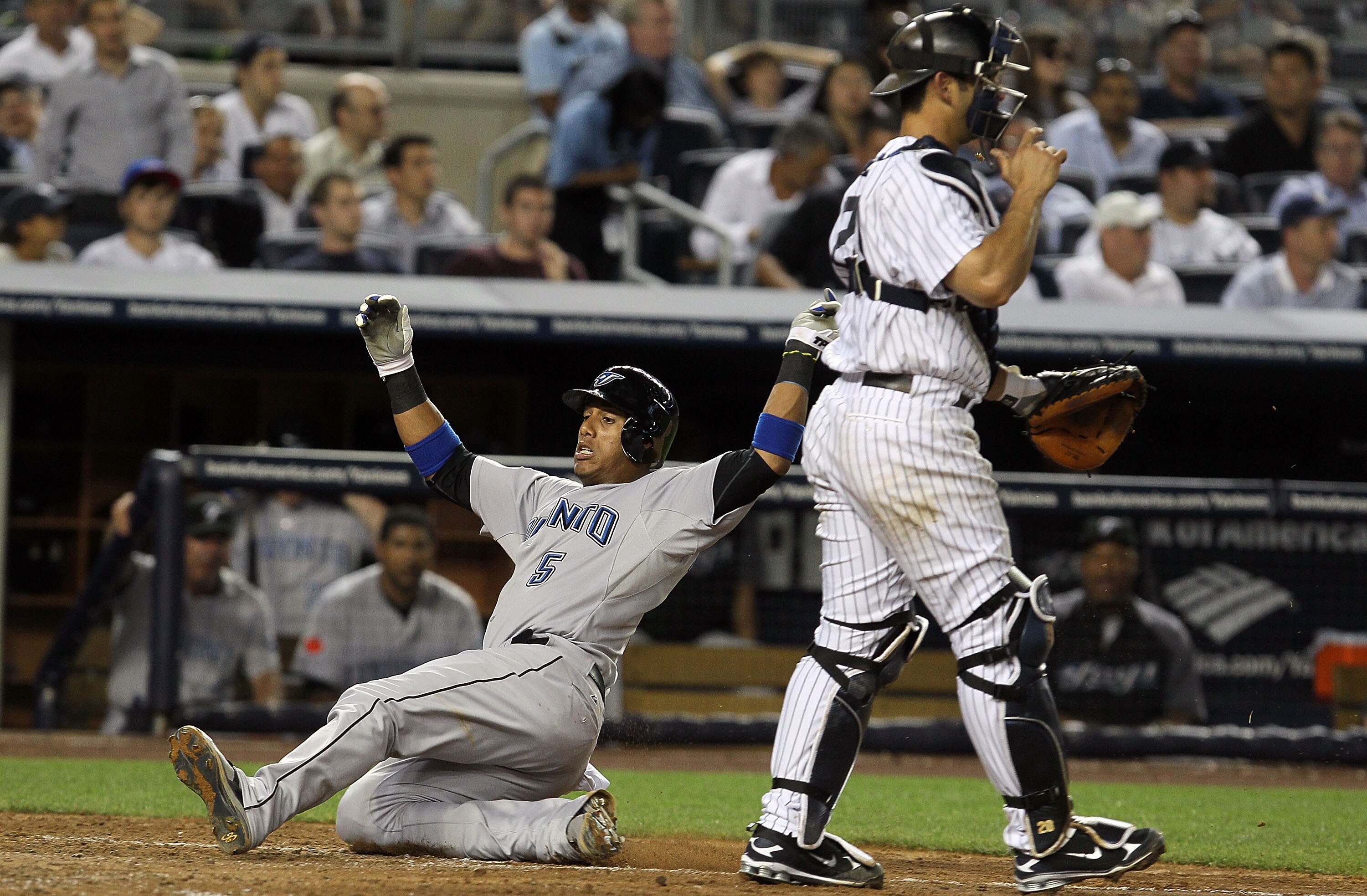NEW YORK - AUGUST 02:  Yunel Escobar #5 of the Toronto Blue Jays scores a run in the fifth inning past Jorge Posada #20 of the New York Yankees on August 2, 2010 at Yankee Stadium in the Bronx borough of New York City.  (Photo by Jim McIsaac/Getty Images)