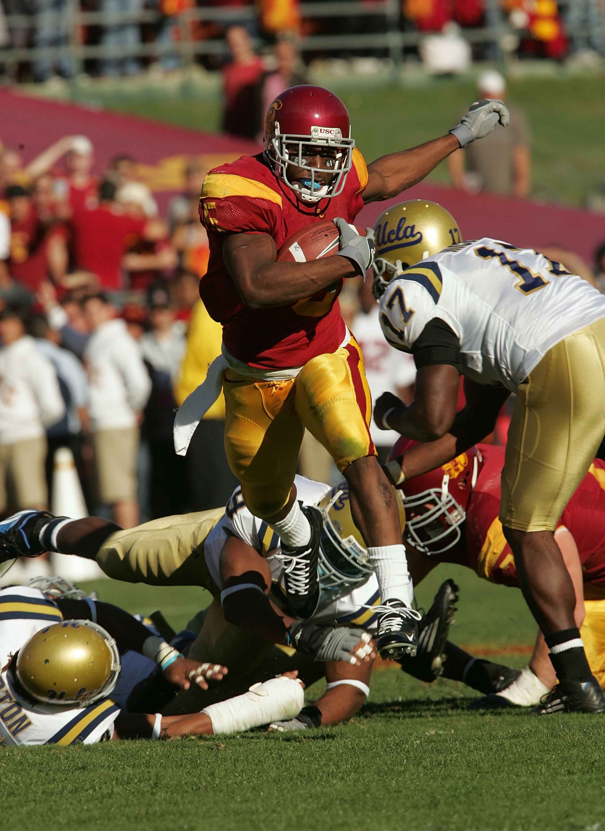 LOS ANGELES, CA - DECEMBER 03:  Reggie Bush #5 of the USC Trojans rushes the ball past the UCLA Bruins defense December 3, 2005 at the Los Angeles Memorial Coliseum in Los Angeles, California.  (Photo by Stephen Dunn/Getty Images)
