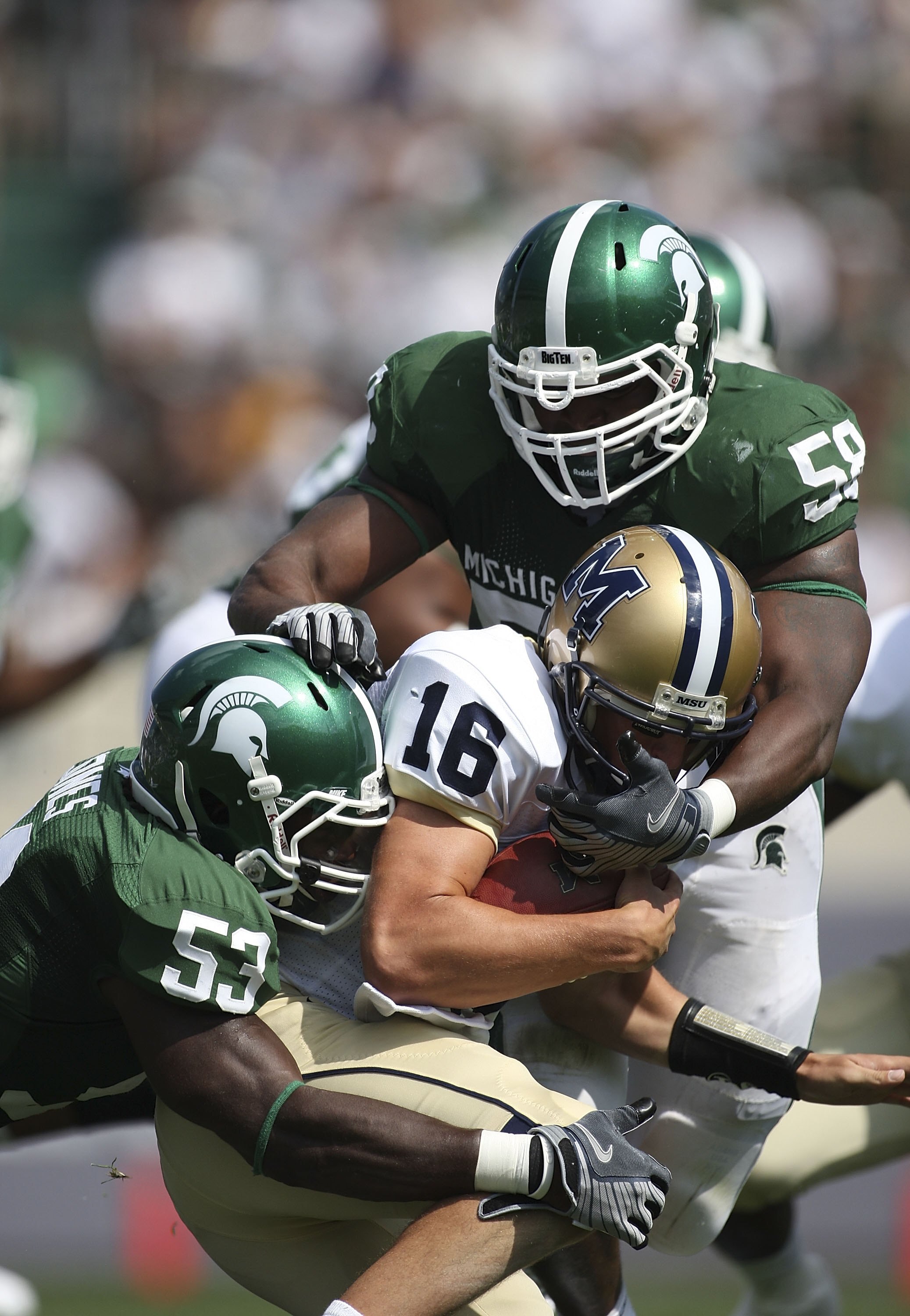 EAST LANSING, MI - SEPTEMBER 05: Tackle D.J. Young #59 and Linebacker Greg Jones #53 of the Michigan State Spartans sack Quarterback Mark Iddins #16 of Montana State during the second quarter on September 5, 2009 at Spartan Stadium in East Lansing, Michig