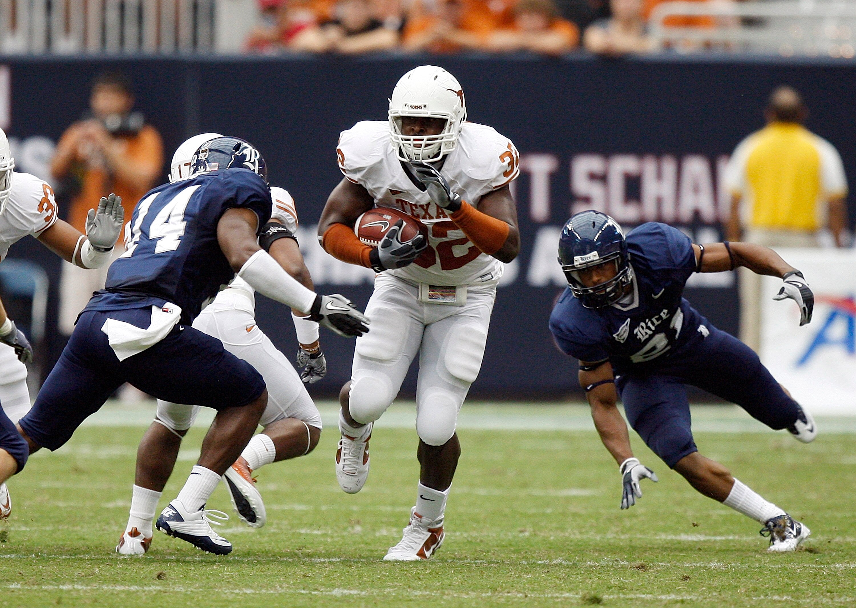 HOUSTON - SEPTEMBER 04:  Running back Traylon Shead #32 of the Texas Longhorns splits the defense of safety Xavier Webb #14 and safety Denzel Wells #21 of the Rice Owls at Reliant Stadium on September 4, 2010 in Houston, Texas. Texas beat Rice 34-17.  (Ph