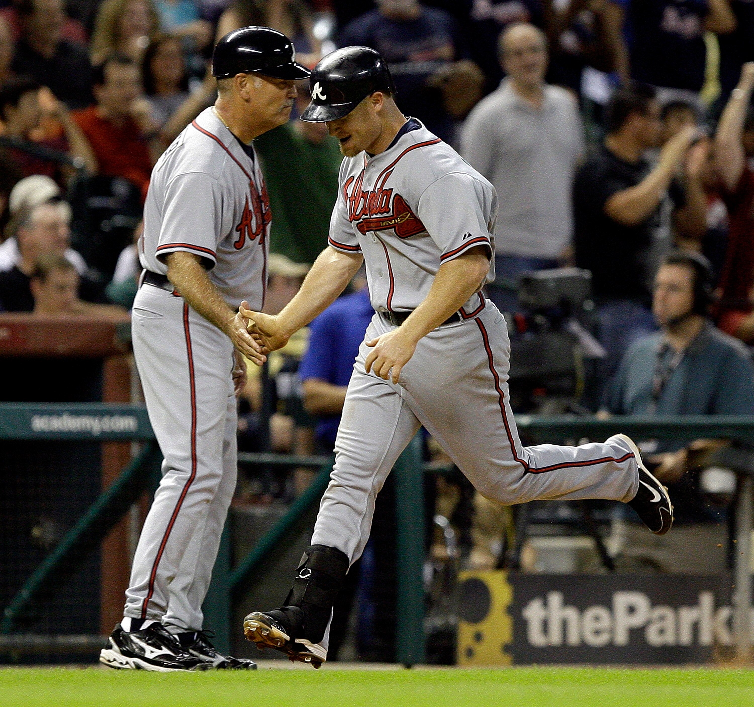HOUSTON - AUGUST 10:  Brooks Conrad #26 of the Atlanta Braves is congratulated by third base coach Brian Snitker after hitting a two run home run in the ninth inning against Matt Lindstrom of the Houston Astros at Minute Maid Park on August 10, 2010 in Ho