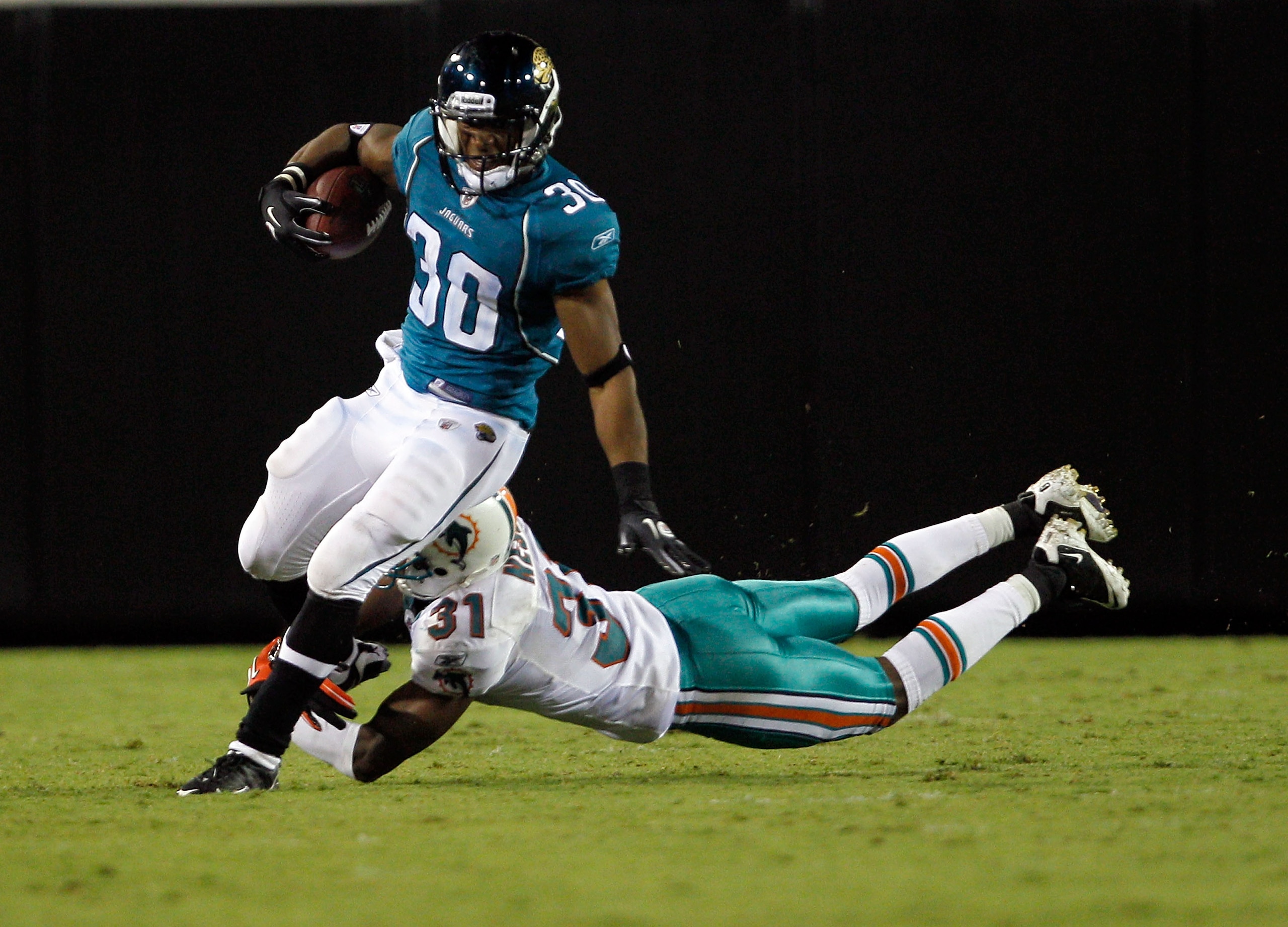 JACKSONVILLE, FL - AUGUST 21:  Nate Ness #31 of the Miami Dolphins attempts to tackle Scotty McGee #30 of the Jacksonville Jaguars during the preseason game at EverBank Field on August 21, 2010 in Jacksonville, Florida.  (Photo by Sam Greenwood/Getty Imag