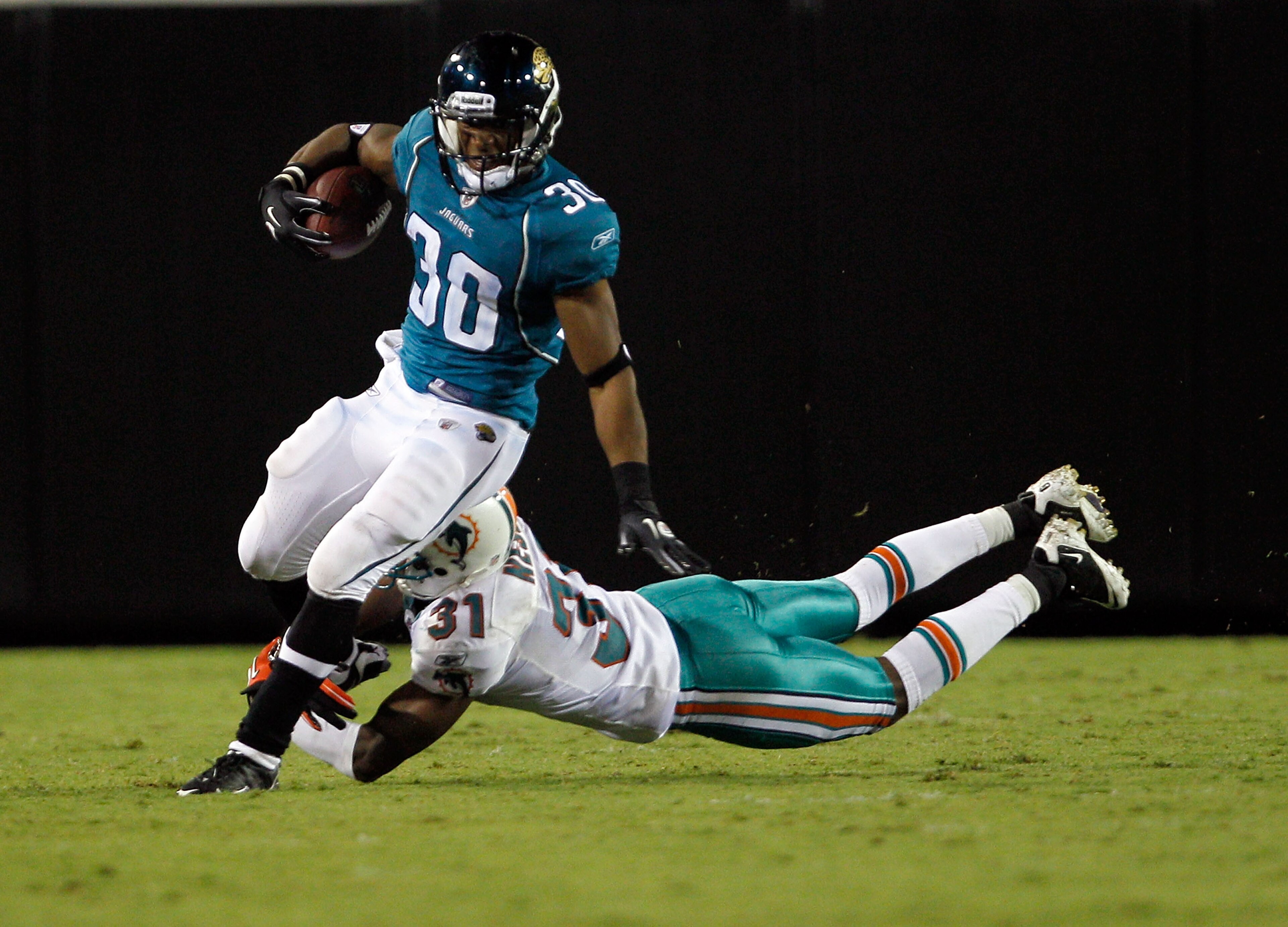 JACKSONVILLE, FL - AUGUST 21:  Nate Ness #31 of the Miami Dolphins attempts to tackle Scotty McGee #30 of the Jacksonville Jaguars during the preseason game at EverBank Field on August 21, 2010 in Jacksonville, Florida.  (Photo by Sam Greenwood/Getty Imag