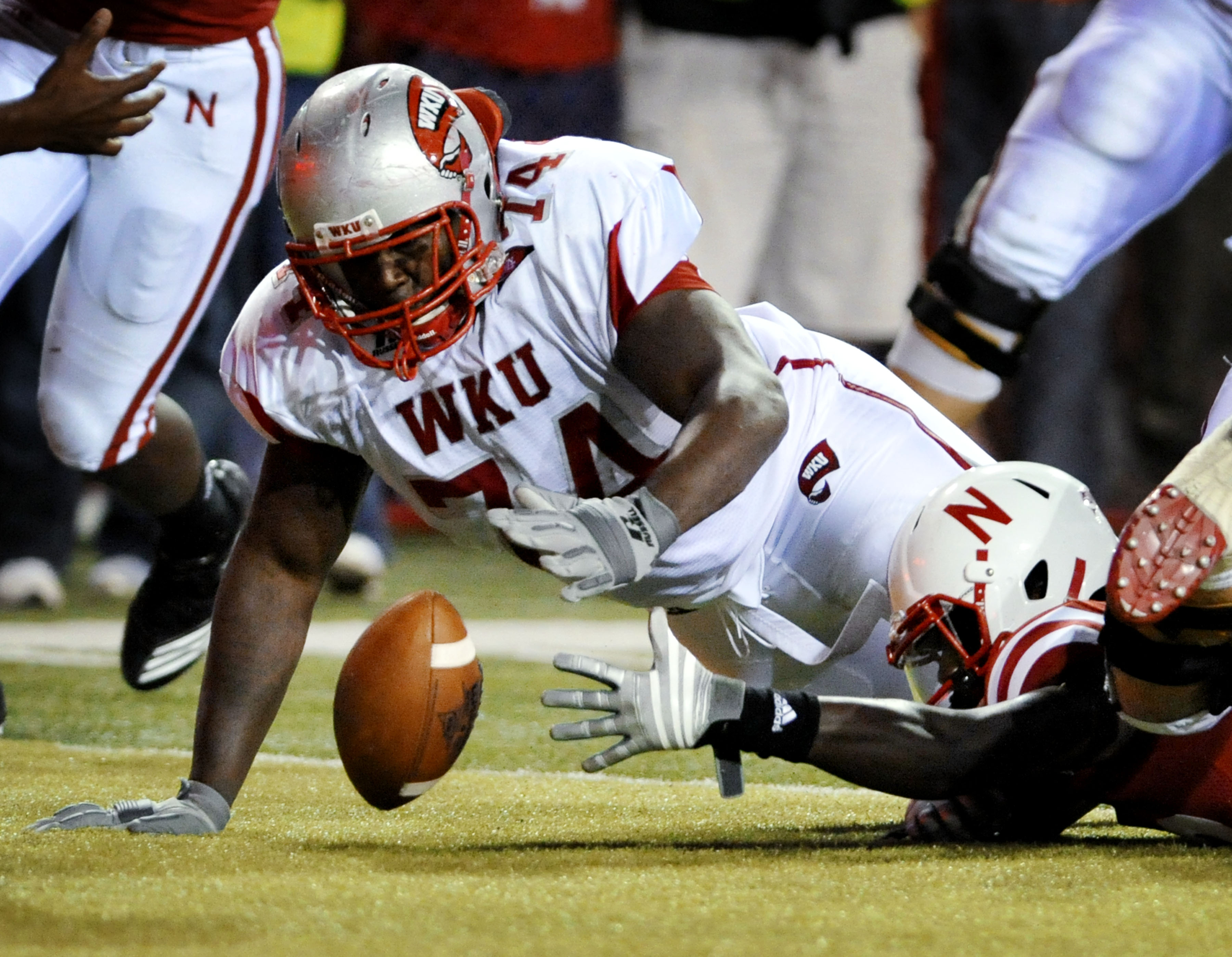 LINCOLN, NE - SEPTEMBER 04: P.J. Smith #13 of the Nebraska Cornhuskers fights for a fumble with Mychal Patterson #74 of the  Western Kentucky Hilltoppers during second half action of their game at Memorial Stadium on September 4, 2010 in Lincoln, Nebraska