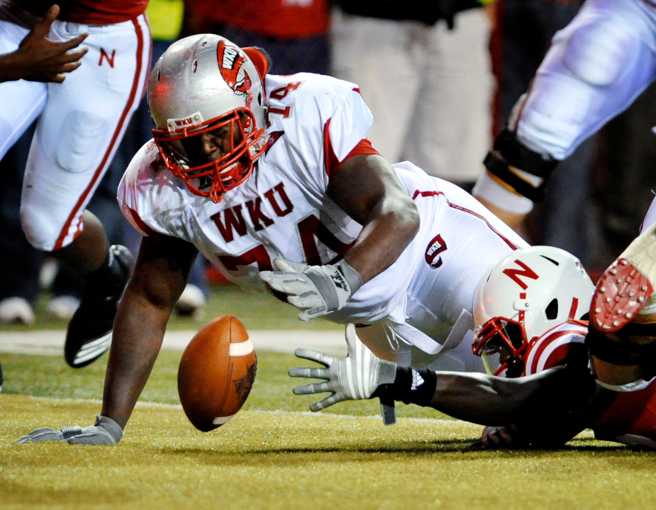 LINCOLN, NE - SEPTEMBER 04: P.J. Smith #13 of the Nebraska Cornhuskers fights for a fumble with Mychal Patterson #74 of the  Western Kentucky Hilltoppers during second half action of their game at Memorial Stadium on September 4, 2010 in Lincoln, Nebraska