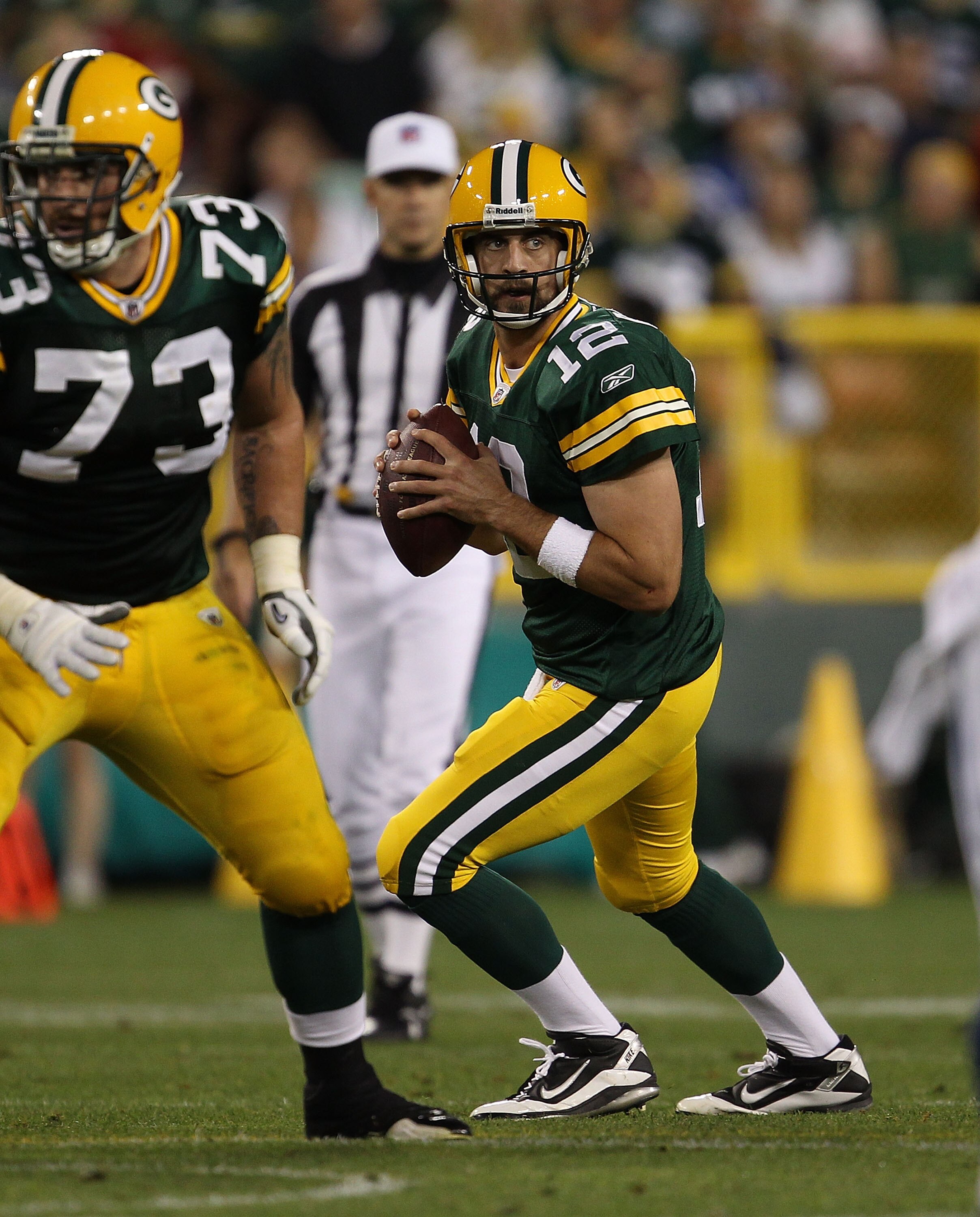 GREEN BAY, WI - AUGUST 26: Aaron Rodgers #12 of the Green Bay Packers drops back to look for a receiver as teammate Daryn Colledge #73 looks to block against the Indianapolis Colts during a preseason game at Lambeau Field on August 26, 2010 in Green Bay, 