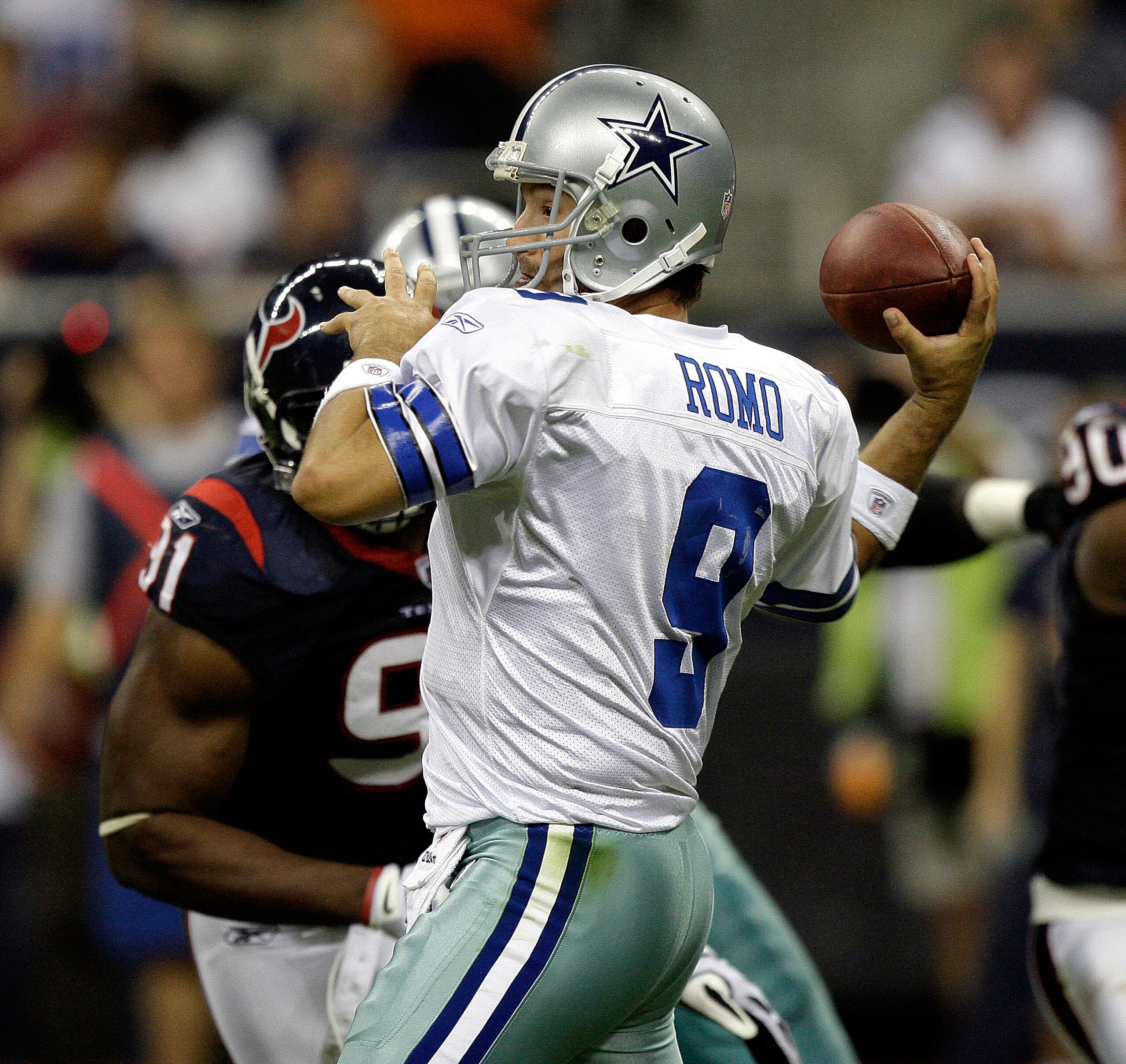HOUSTON - AUGUST 28: Quarterback Tony Romo #9 of the Dallas Cowboys looks fora receiver as he receives some pressure from defensive tackle Amobi Akoye #91 of the Houston Texans during a football game against the Houston Texans at Reliant Stadium on August