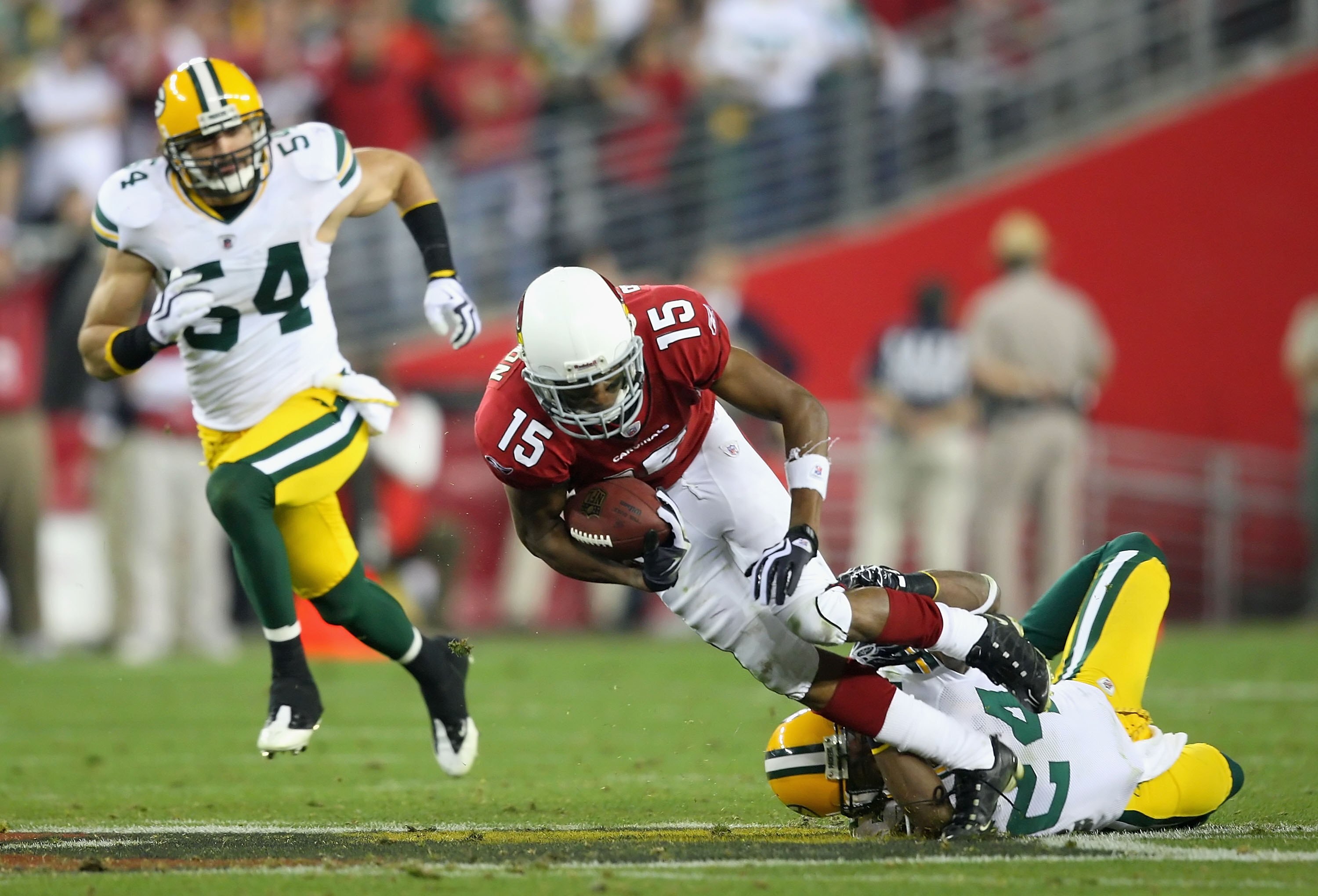 GLENDALE, AZ - JANUARY 10:  Wide receiver Steve Breaston #15 of the Arizona Cardinals is tackled by Jarrett Bush #24 of the Green Bay Packers after a reception during the 2010 NFC wild-card playoff game at the Universtity of Phoenix Stadium on January 10,