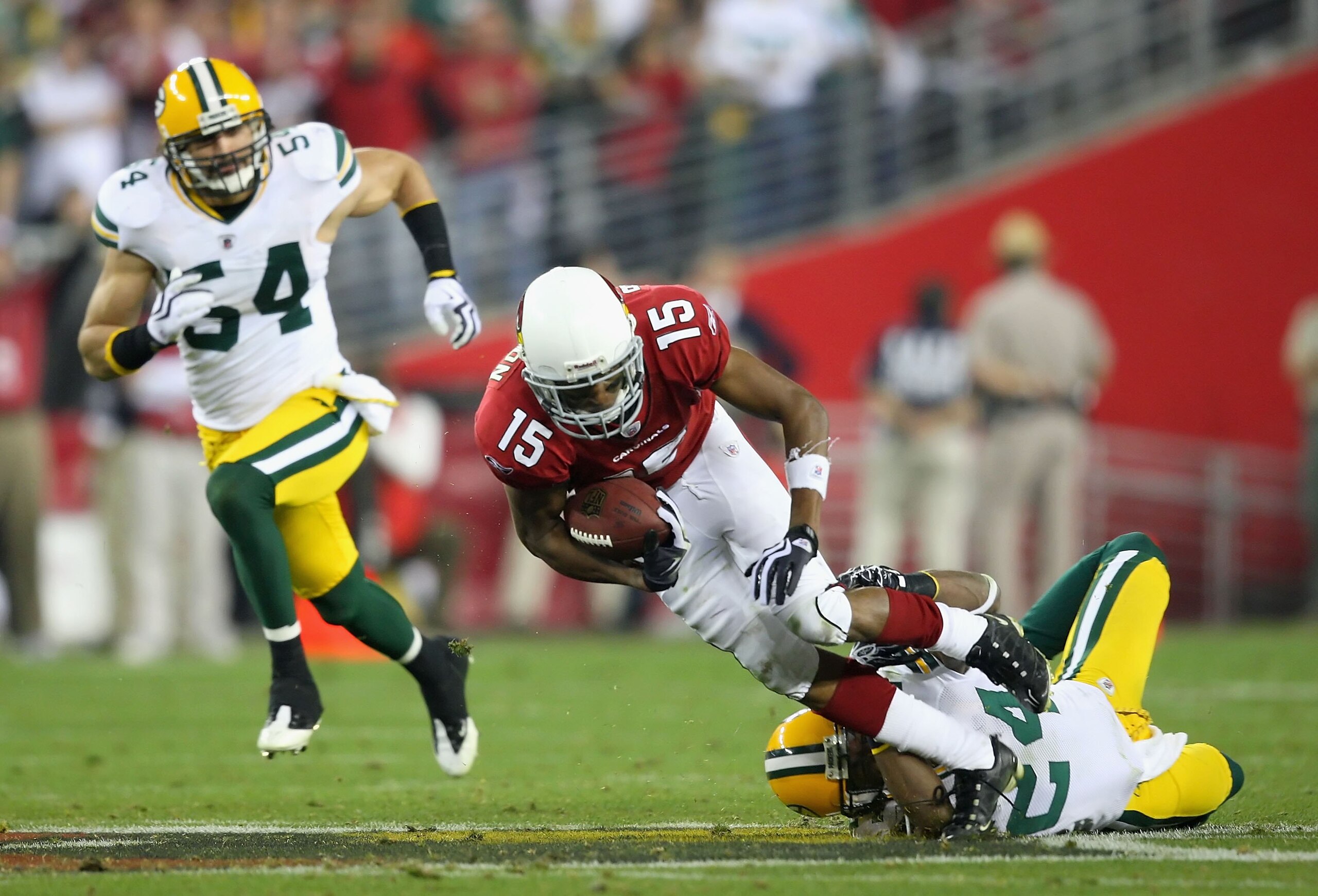 GLENDALE, AZ - JANUARY 10:  Wide receiver Steve Breaston #15 of the Arizona Cardinals is tackled by Jarrett Bush #24 of the Green Bay Packers after a reception during the 2010 NFC wild-card playoff game at the Universtity of Phoenix Stadium on January 10,