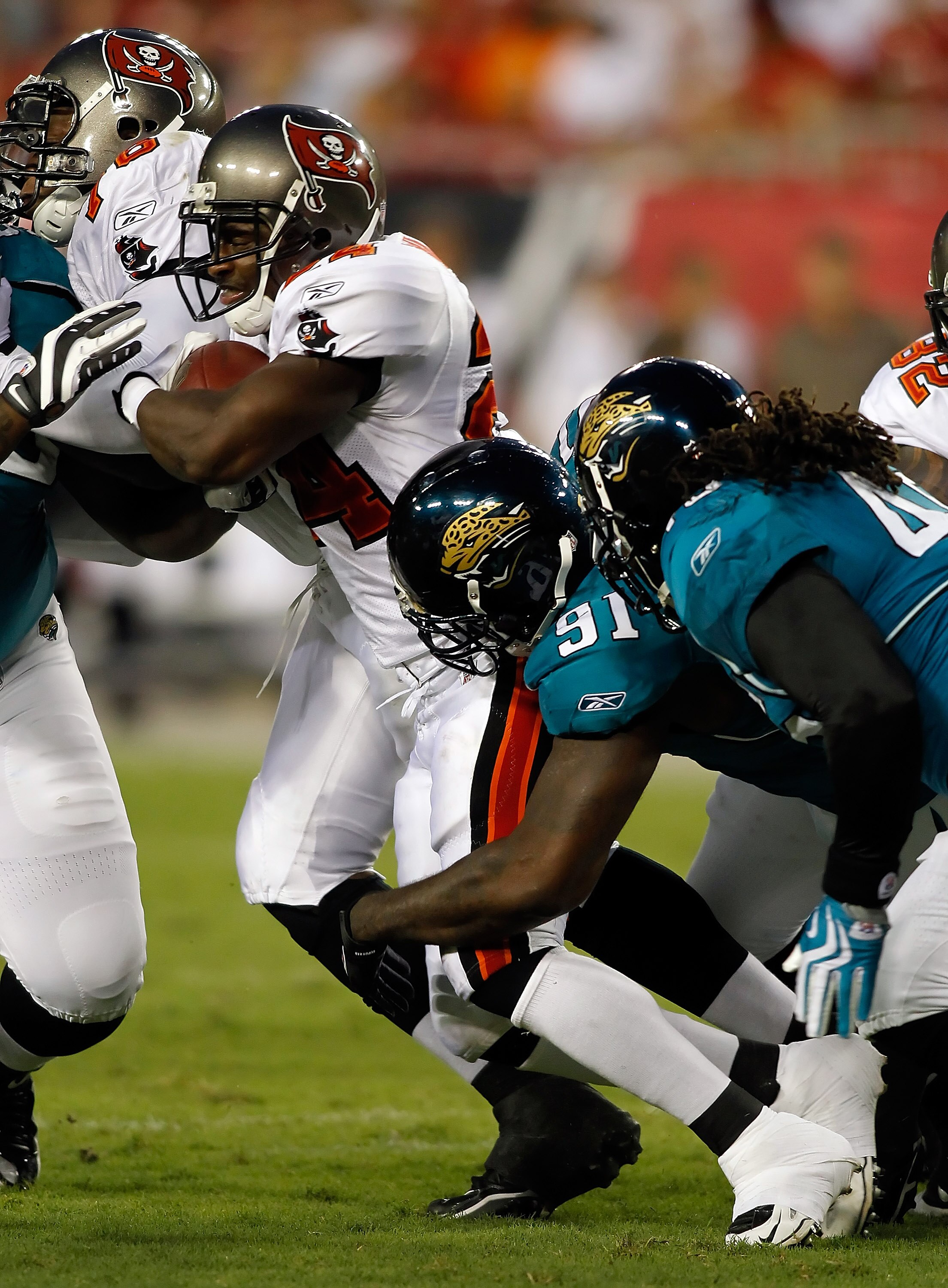 TAMPA, FL - AUGUST 28:  Running back Carnell Williams #24 of the Tampa Bay Buccaneers is tackled by defensive end Derrick Harvey #91 of the Jacksonville Jaguars during a preseason game at Raymond James Stadium on August 28, 2010 in Tampa, Florida.  (Photo