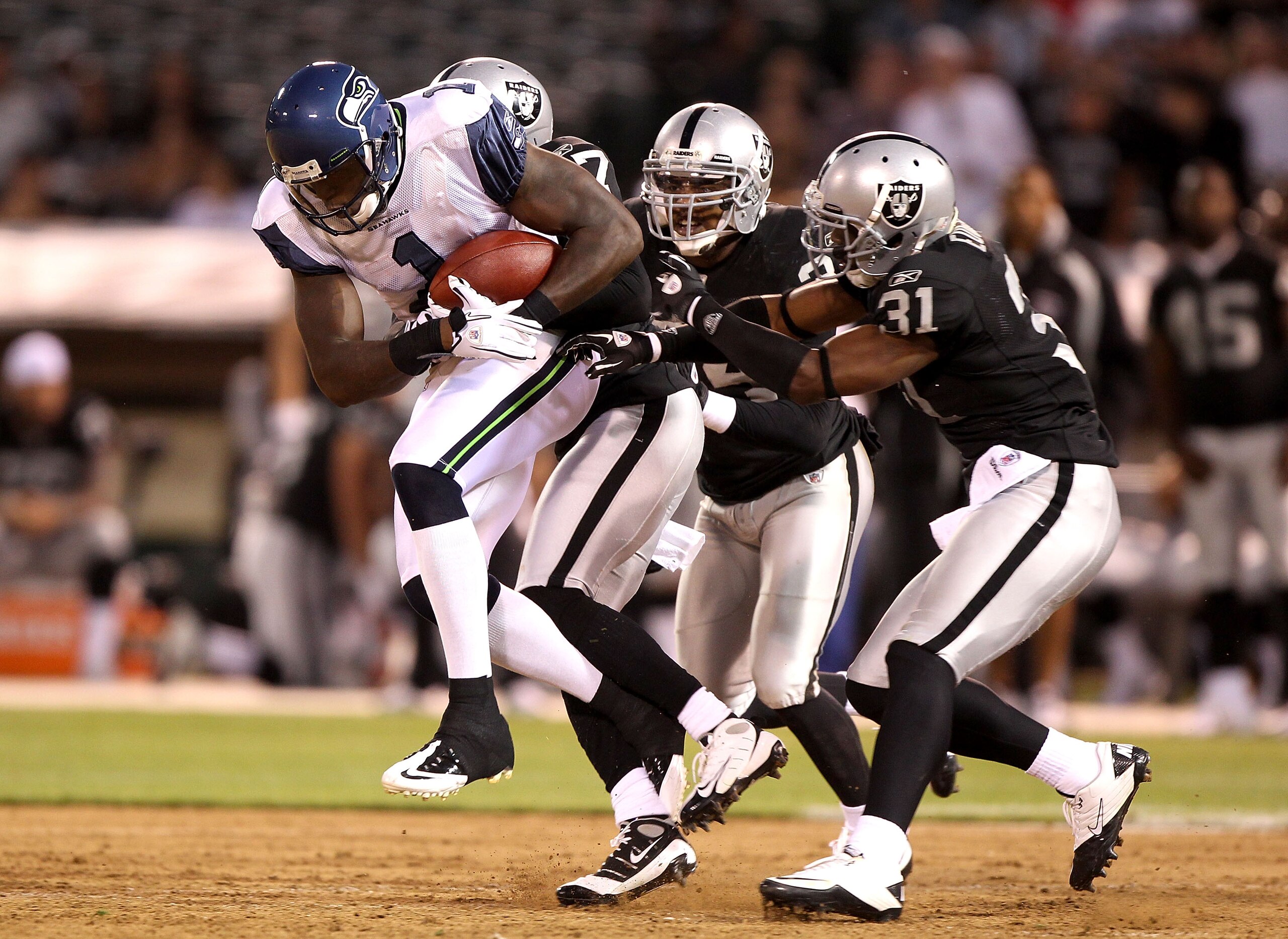 OAKLAND, CA - SEPTEMBER 02:  Mike Williams #1 of the Seattle Seahawks runs after a catch against Hiram Eugene #31 of the Oakland Raiders defends during an NFL preseason game at Oakland-Alameda County Coliseum on September 2, 2010 in Oakland, California.
