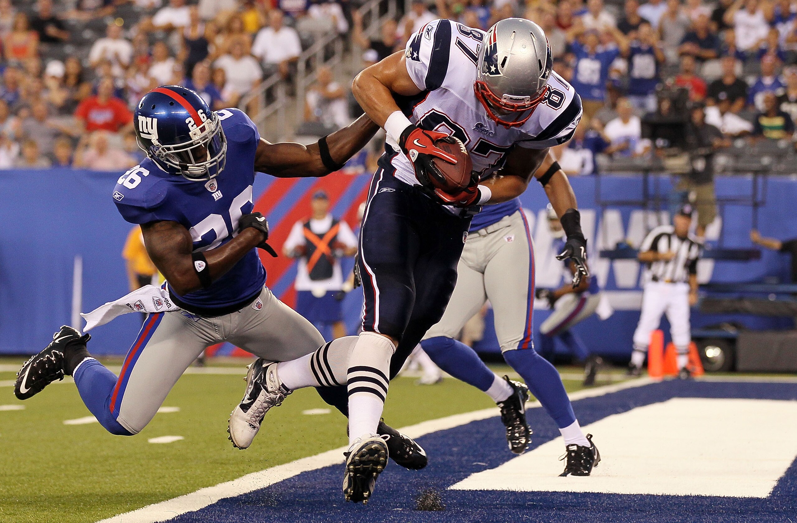 EAST RUTHERFORD, NJ - SEPTEMBER 02:  Rob Gronkowski #87 of the New England Patriots carries a reception into the endzone past Antrel Rolle #26 of the New York Giants for a first quarter touchdown on September 2, 2010 at the New Meadowlands Stadium in East