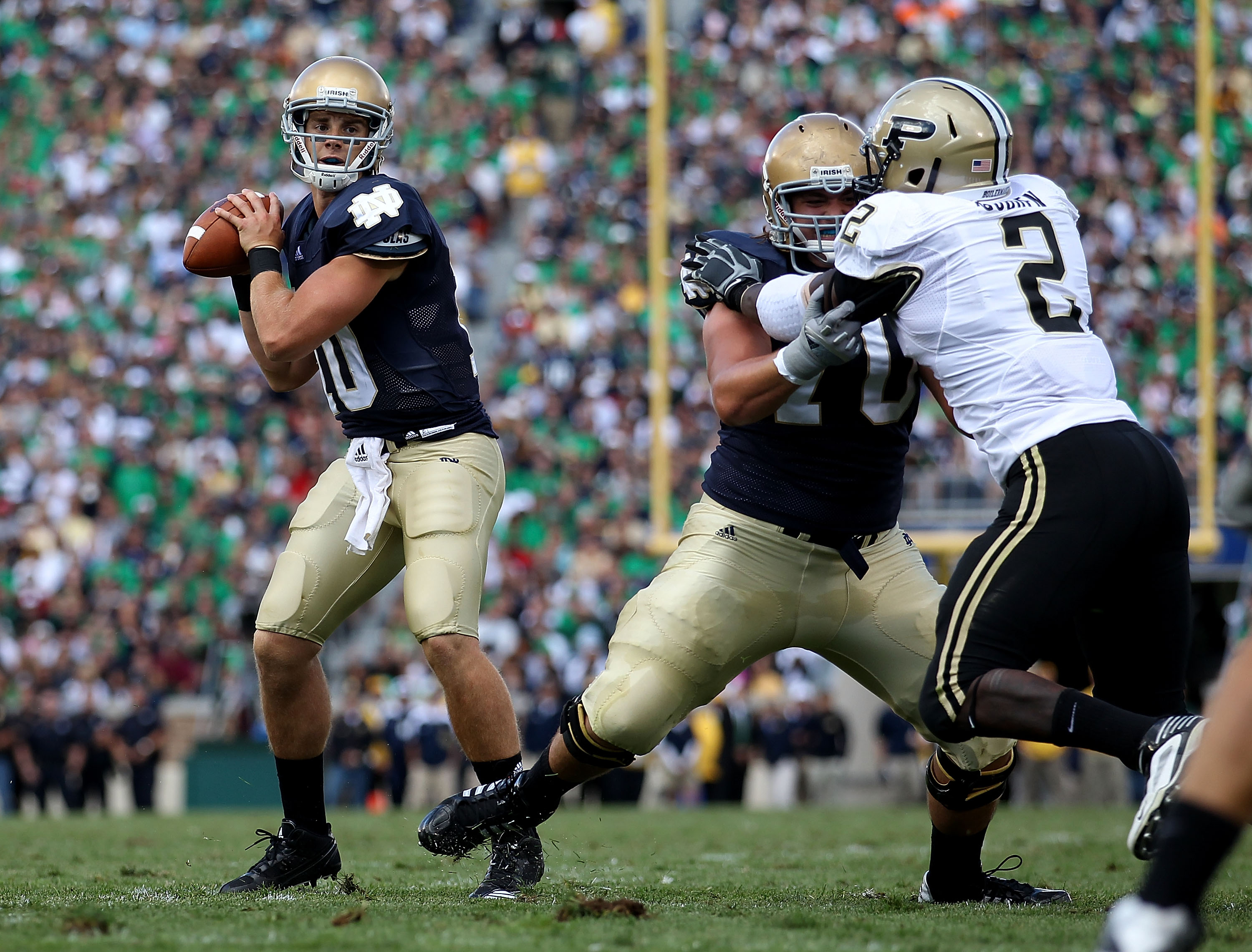 SOUTH BEND, IN - SEPTEMBER 04: Dayne Crist #10 of the Notre Dame Fighting Irish looks for a receiver as teammate Zack Martin #70 blocks Gerald Gooden #2 of the Purdue Boilermakers at Notre Dame Stadium on September 4, 2010 in South Bend, Indiana. Notre Da