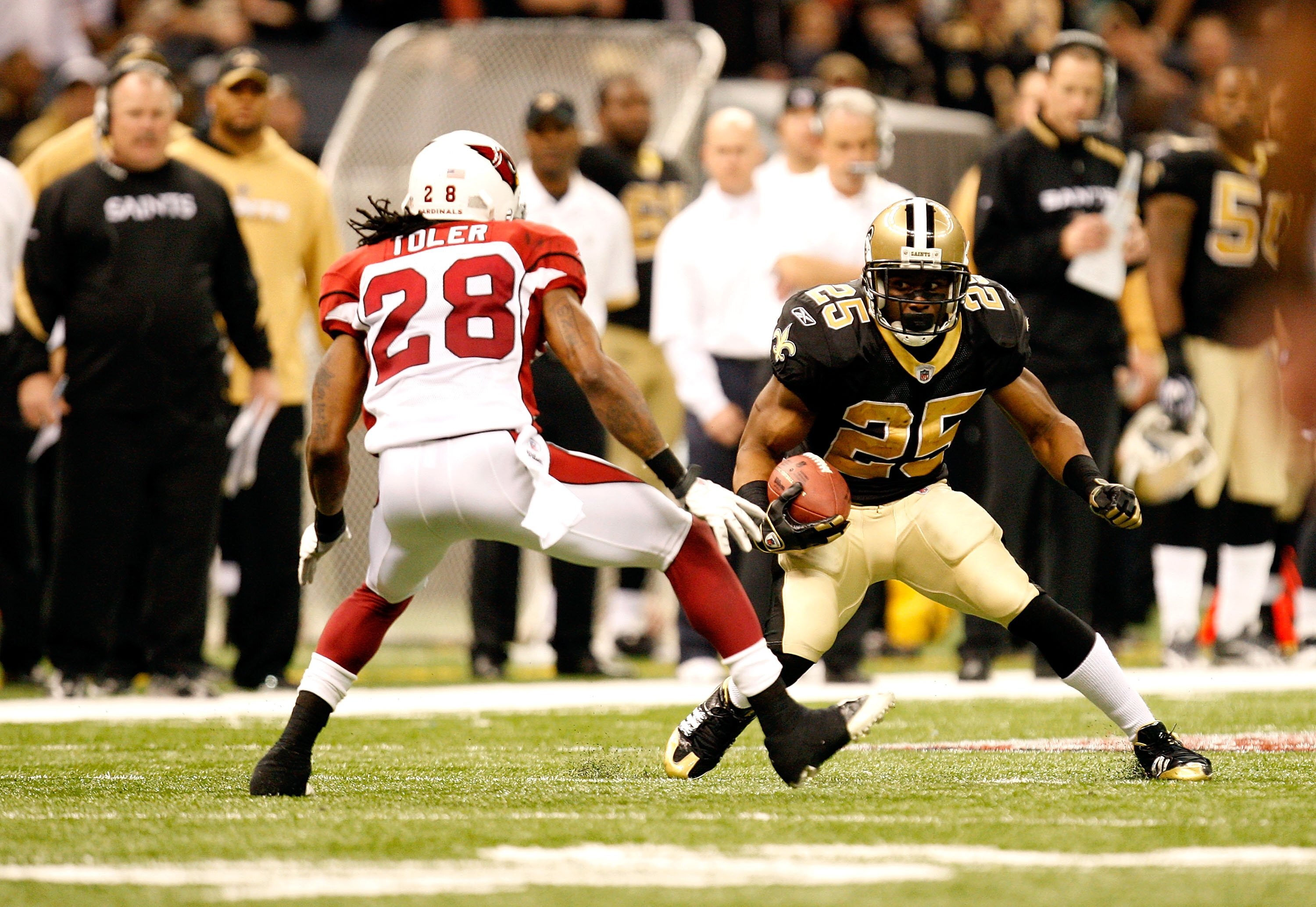 NEW ORLEANS - JANUARY 16:  Reggie Bush #25 of the New Orleans Saints runs the ball against Greg Toler #28 of the Arizona Cardinals during the NFC Divisional Playoff Game at Louisana Superdome on January 16, 2010 in New Orleans, Louisiana. The Saints won 4