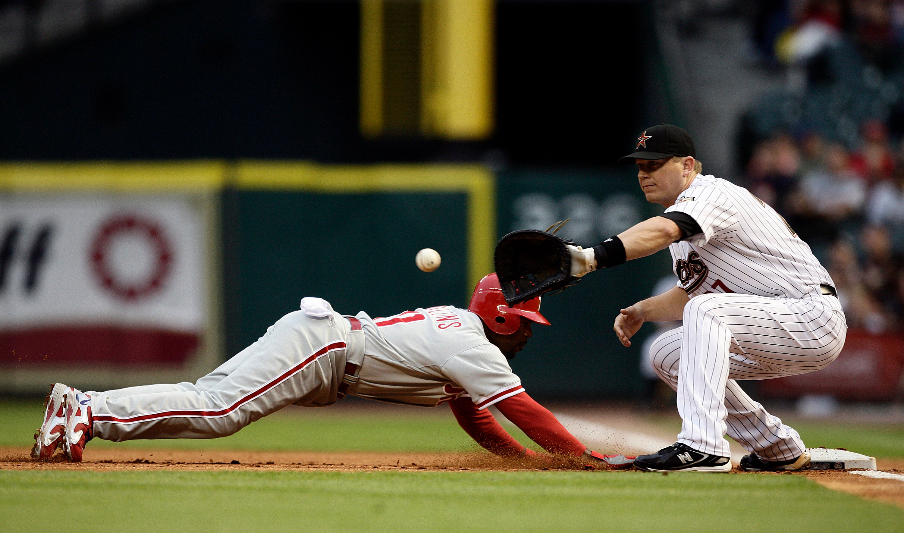 HOUSTON - APRIL 09:  Jimmy Rollins #11 of the Philadelphia Phillies dives back into first base as Geoff Blum #27 awaits the throw at Minute Maid Park on April 9, 2010 in Houston, Texas.  (Photo by Bob Levey/Getty Images)